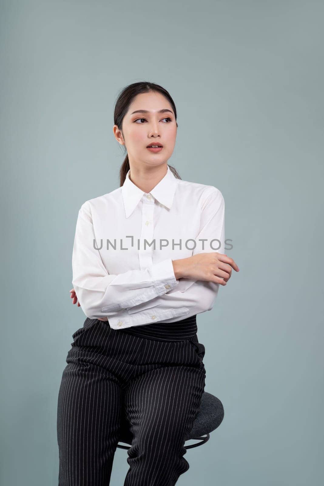 Confident young businesswoman sitting on isolated background. Enthusiastic by biancoblue