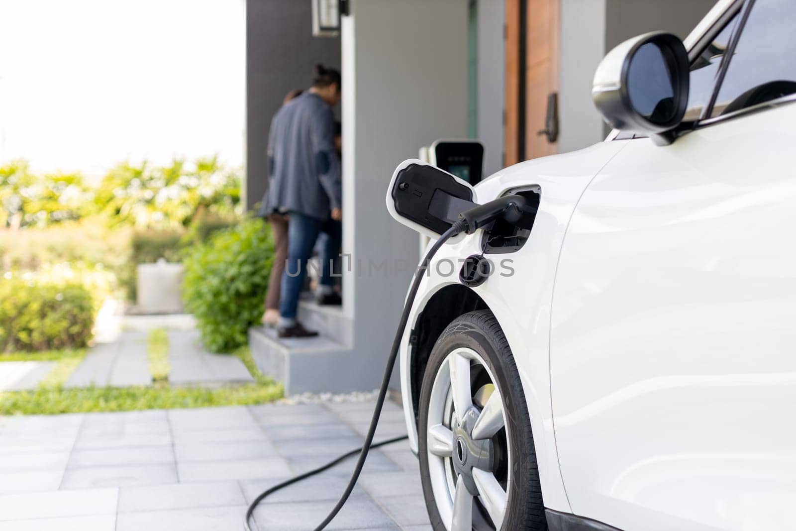 Focus home charging station for EV car, blur progressive family in background. by biancoblue