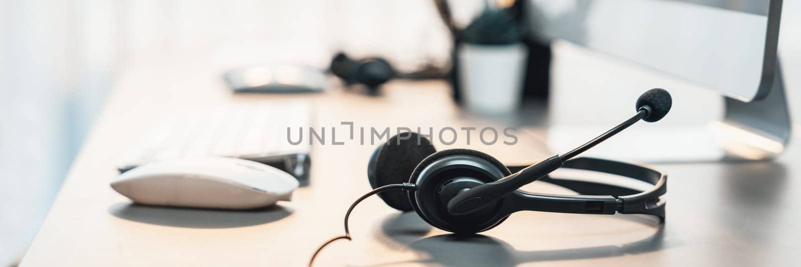 Panorama view of empty call center operator workspace focus on headset. Prodigy by biancoblue