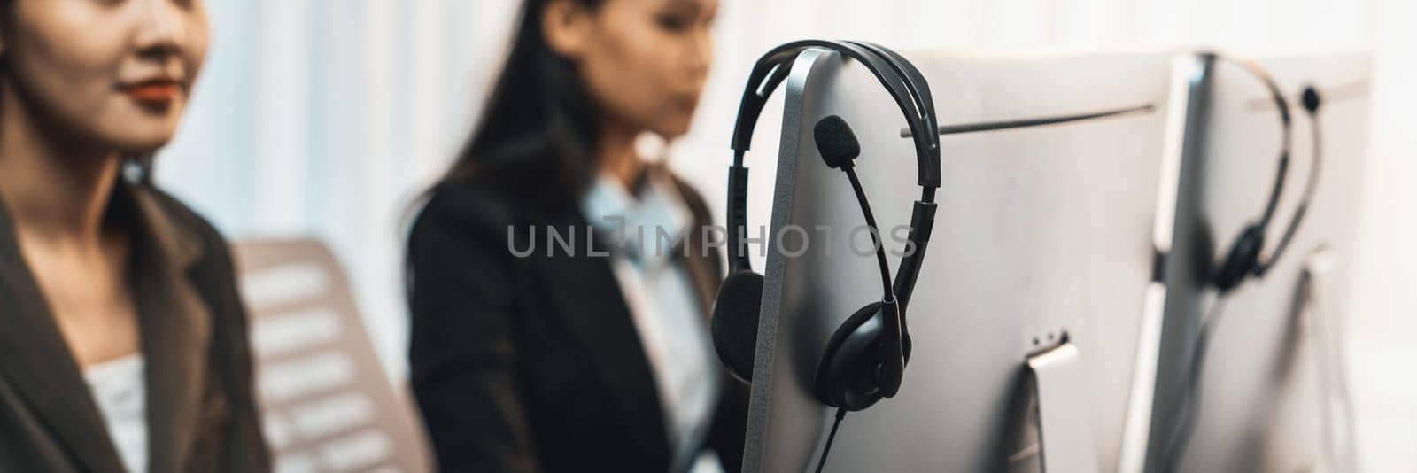 Panorama focus headset on call center workspace desk with blur background of operator team or telesales representative engage in providing client with customer support service or making sales. Prodigy