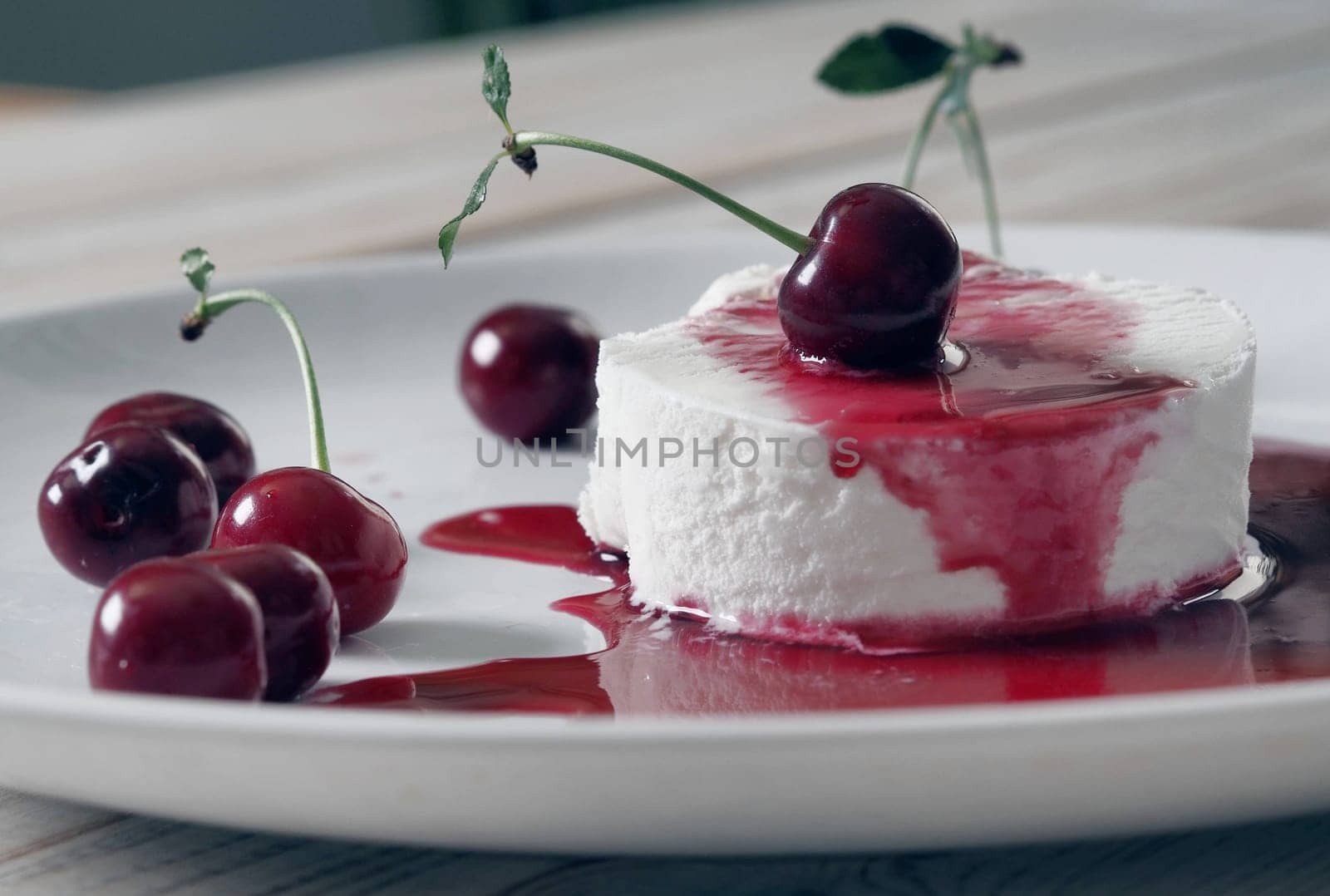 Food background.Ice cream with cherries on a white plate, poured with red jam.Side view