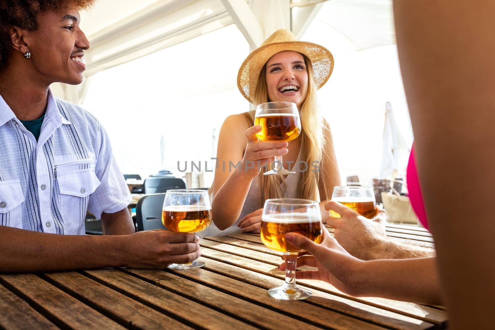 Summer vacation with friends drinking beer and enjoying life at beach bar. by Hoverstock