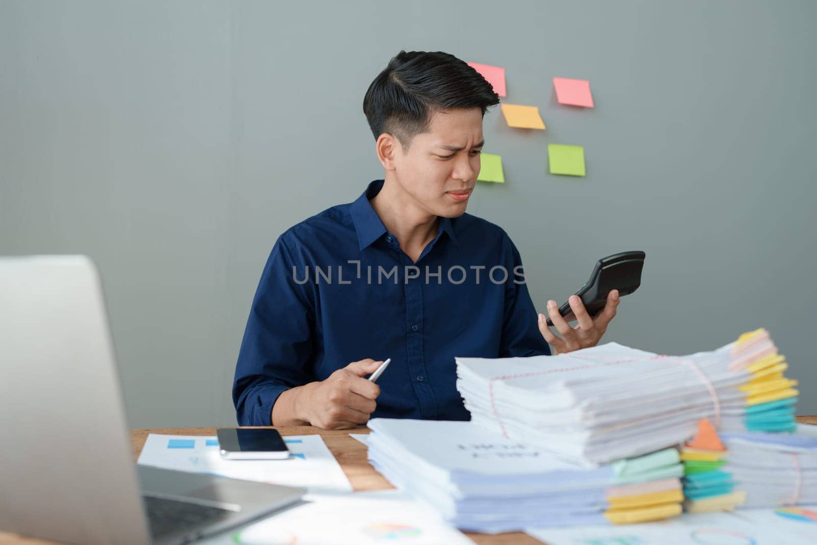 Portrait of business owner, man using computer and financial statements Anxious expression on expanding the market to increase the ability to invest in business. by Manastrong