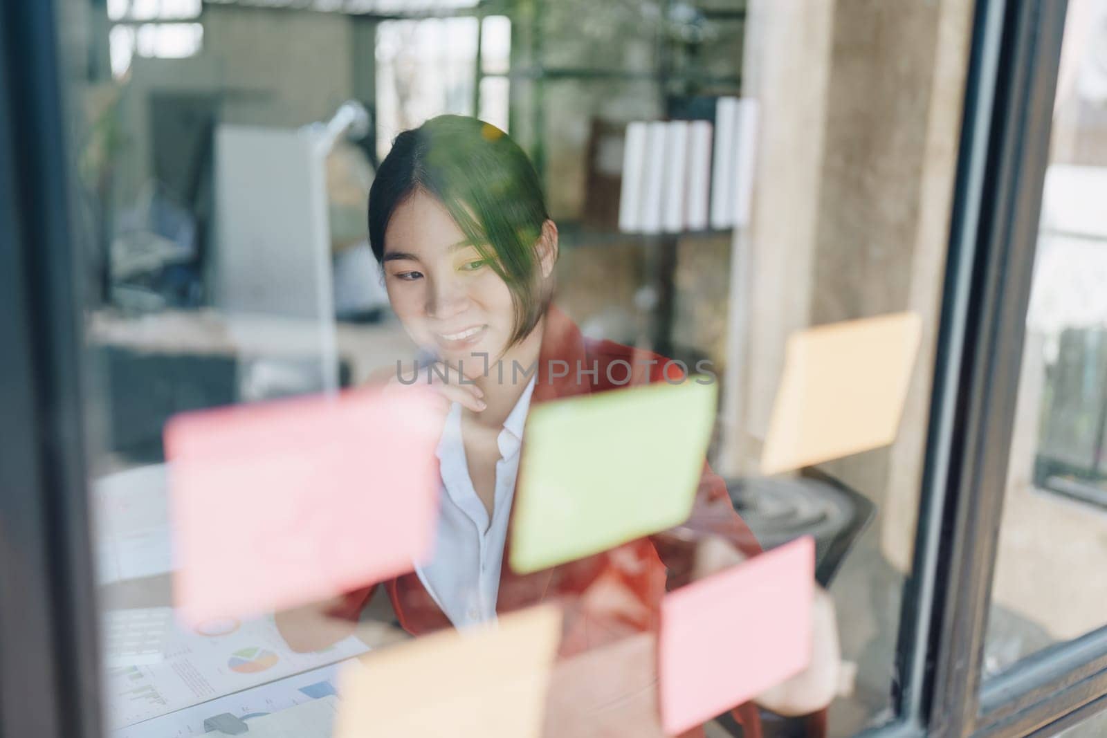 Beautiful young teen asian businesswoman using note pad thinking with planning working on financial document, tax, exchange, accounting and Financial advisor by Manastrong