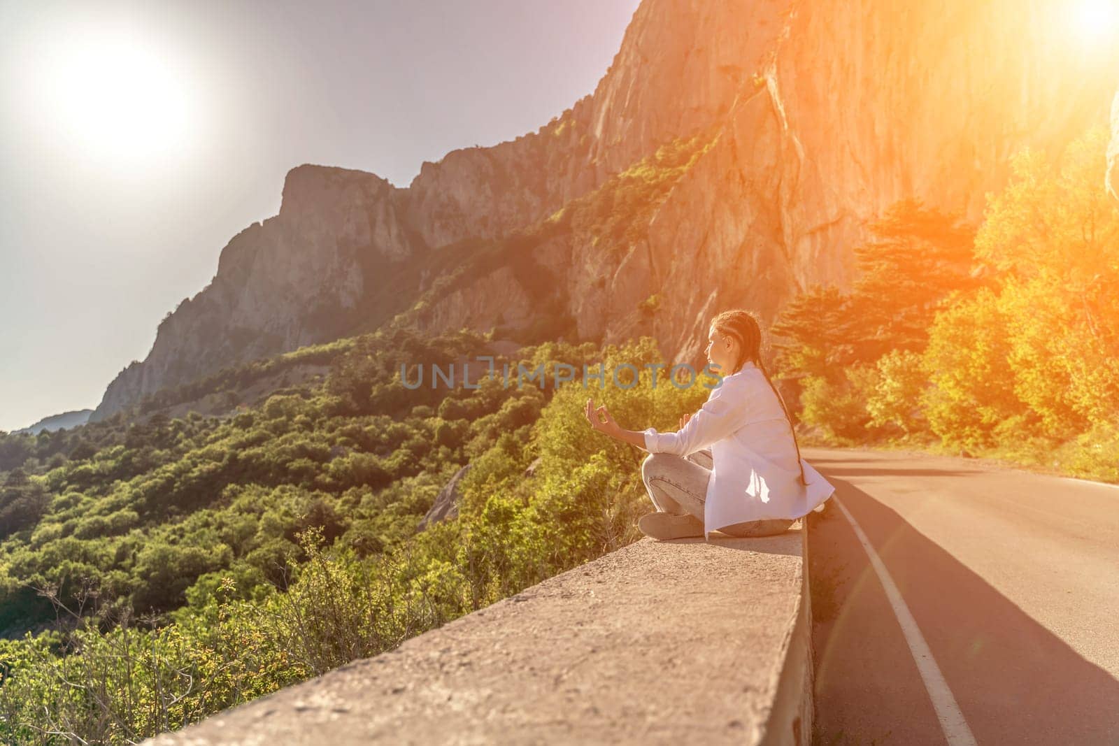 Yoga woman mountains. Profile of a woman doing yoga in the top of a cliff in the mountain. Woman meditates in yoga asana Padmasana.