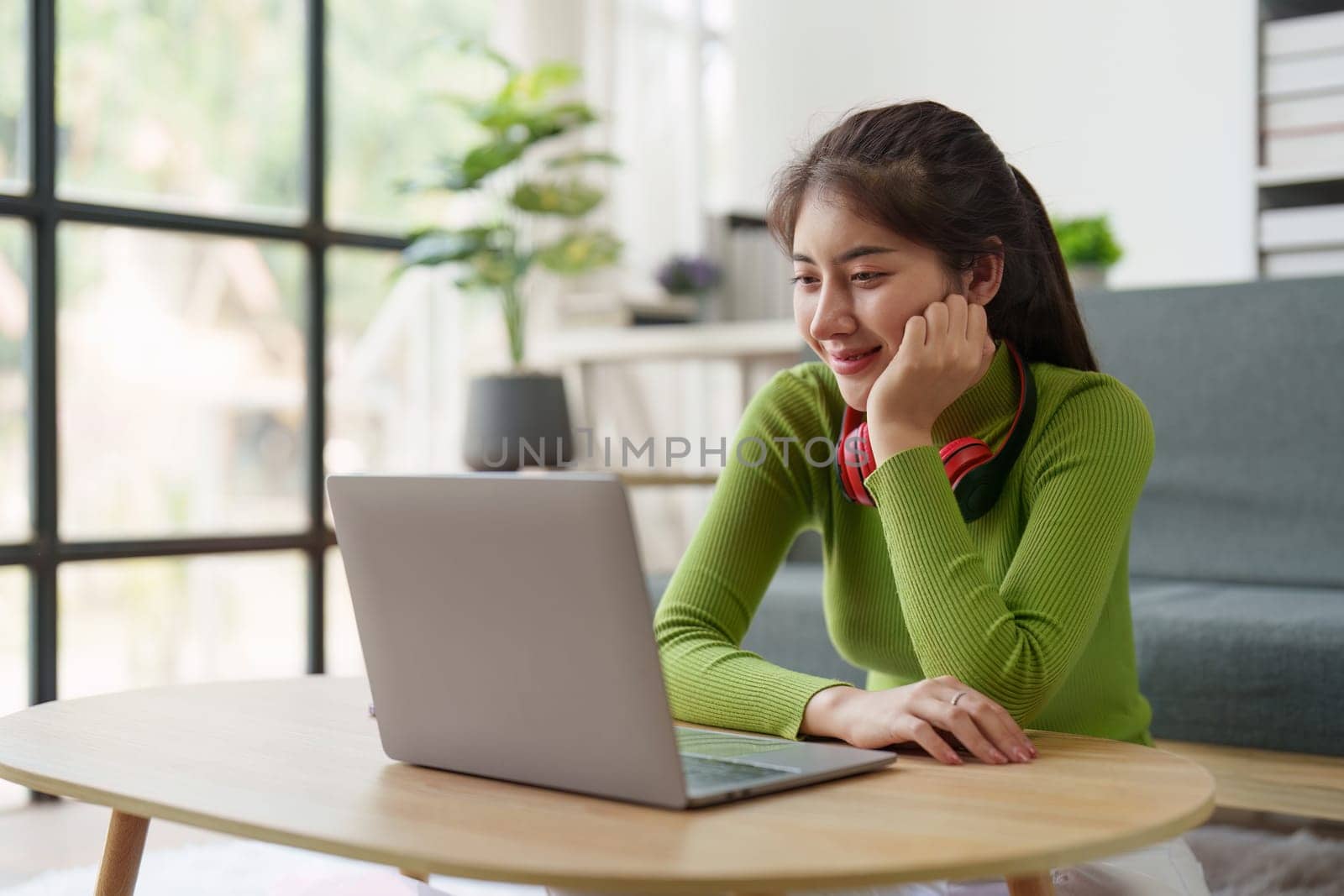 Young asian relaxed smiling pretty woman relaxing with laptop at home. Female feeling joy enjoying with mobile phone on cozy couch.