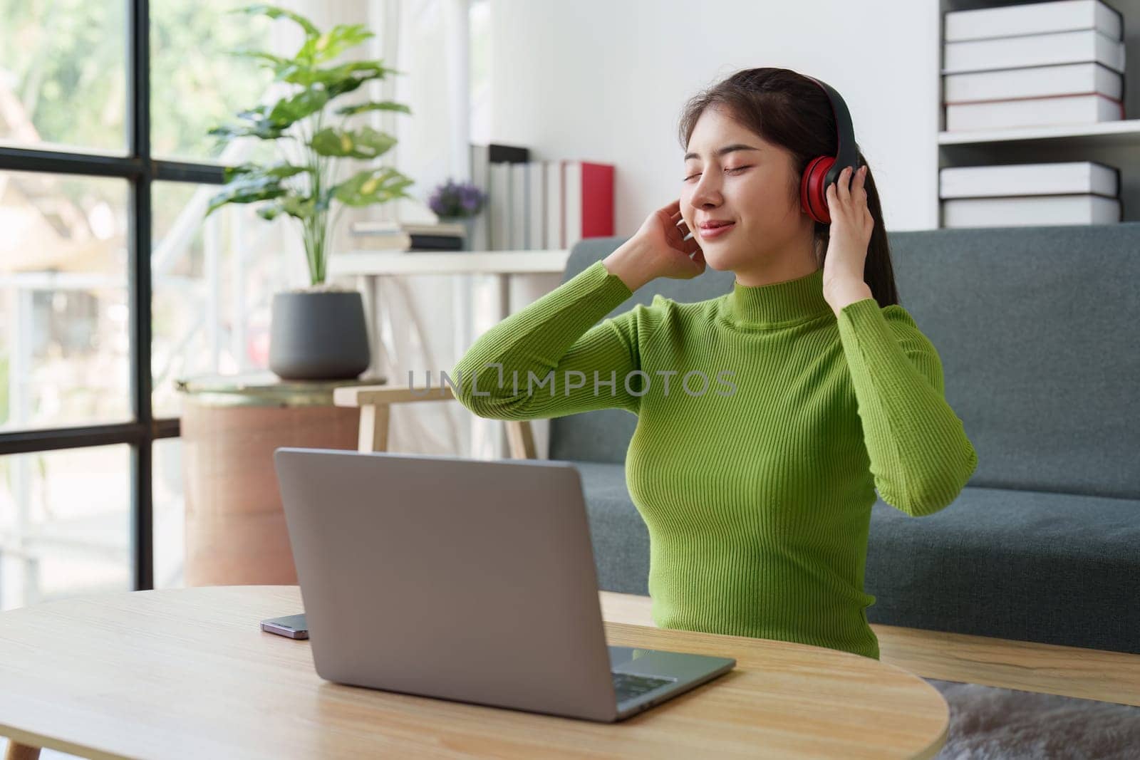 Young asian relaxed smiling pretty woman relaxing with laptop at home. Female feeling joy enjoying with mobile phone on cozy couch.