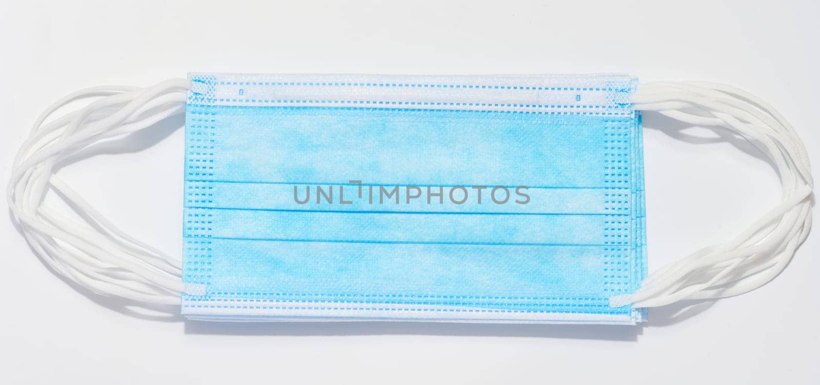 Disposable blue medical face mask against virus protection on a white background, top view by ndanko