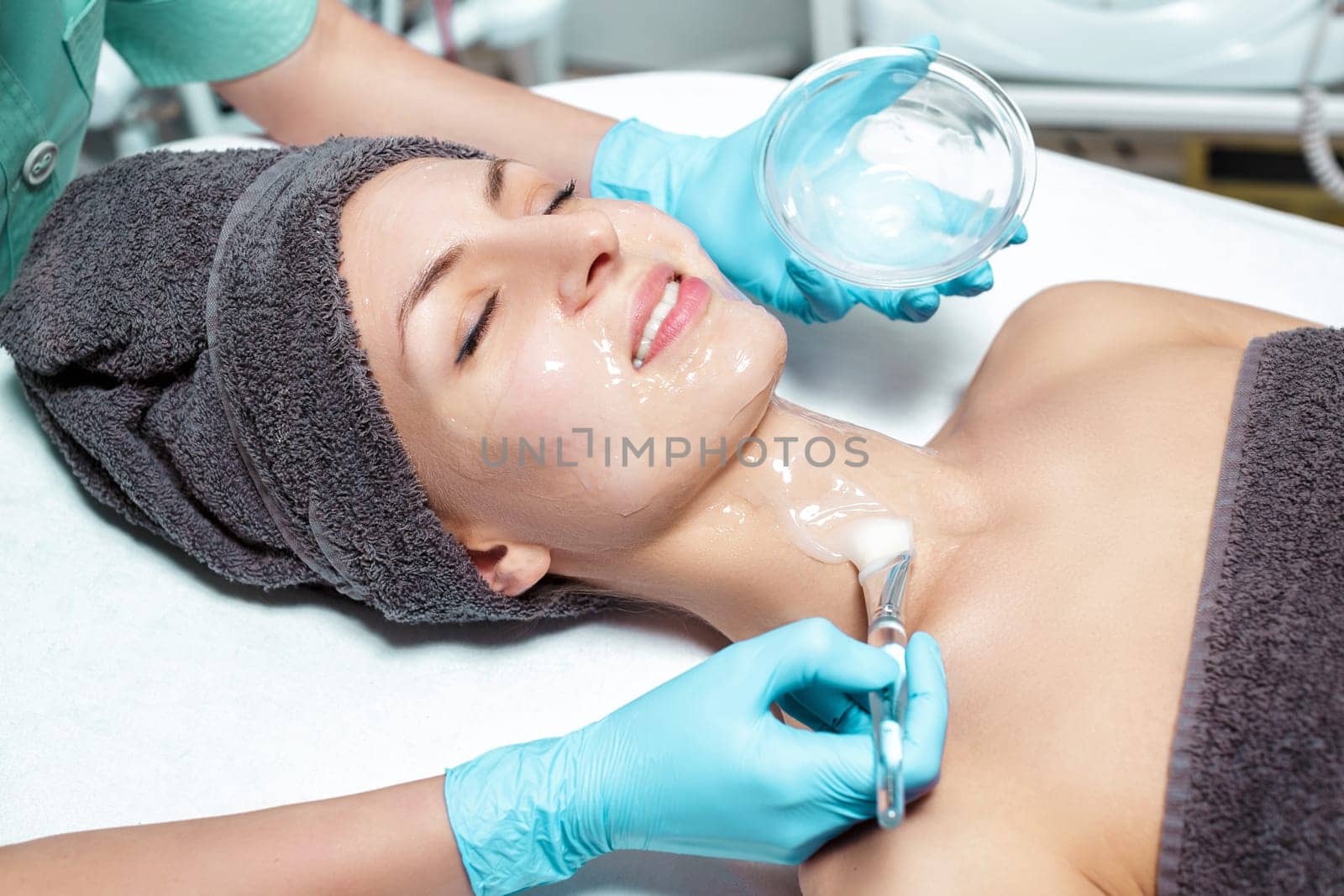 beautician applies face mask with a brush to the beautiful young woman in Spa salon. cosmetic procedure skin care. Microdermabrasion
