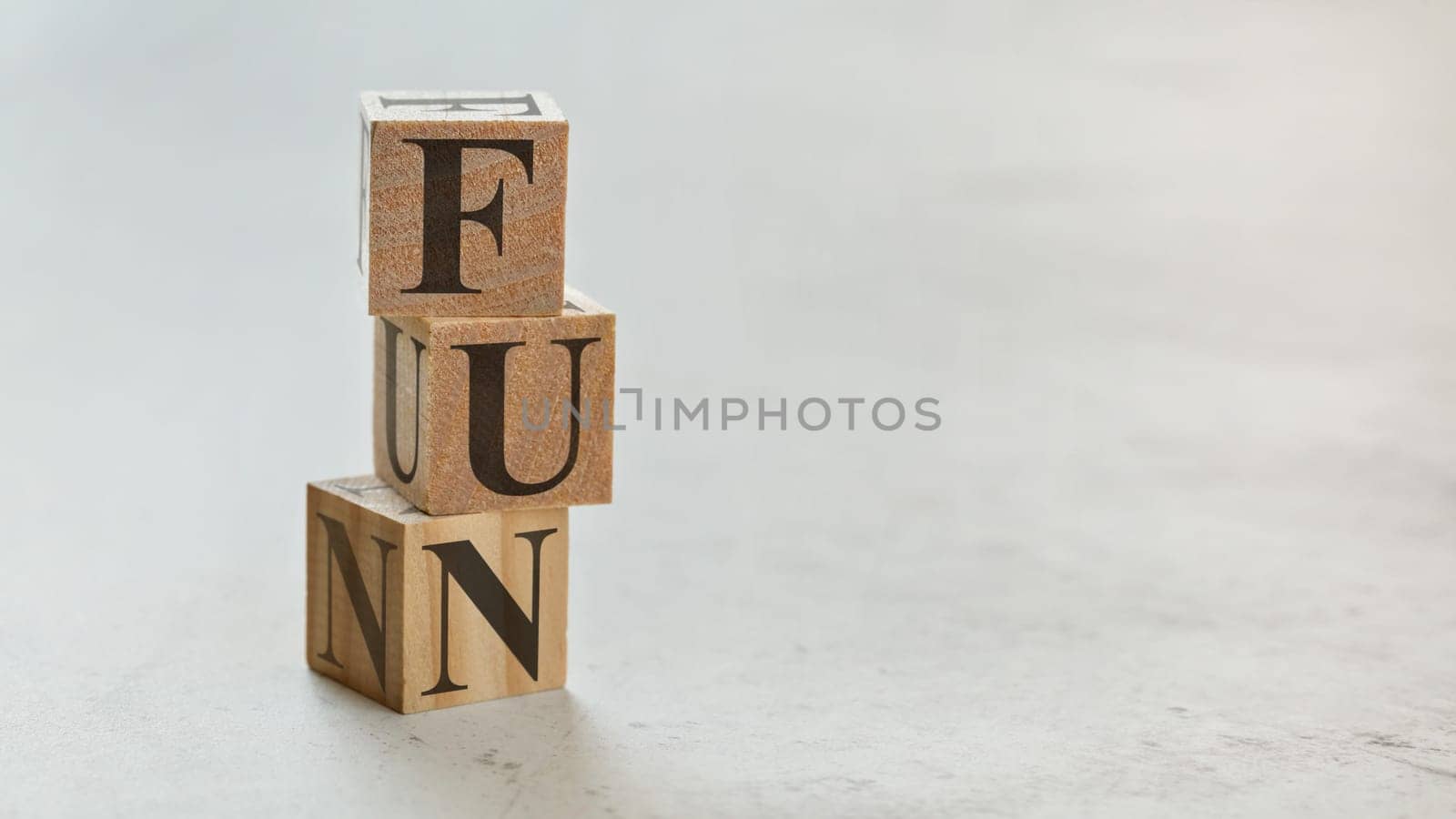Pile with three wooden cubes - letters FUN on them, space for more text / images on right side.