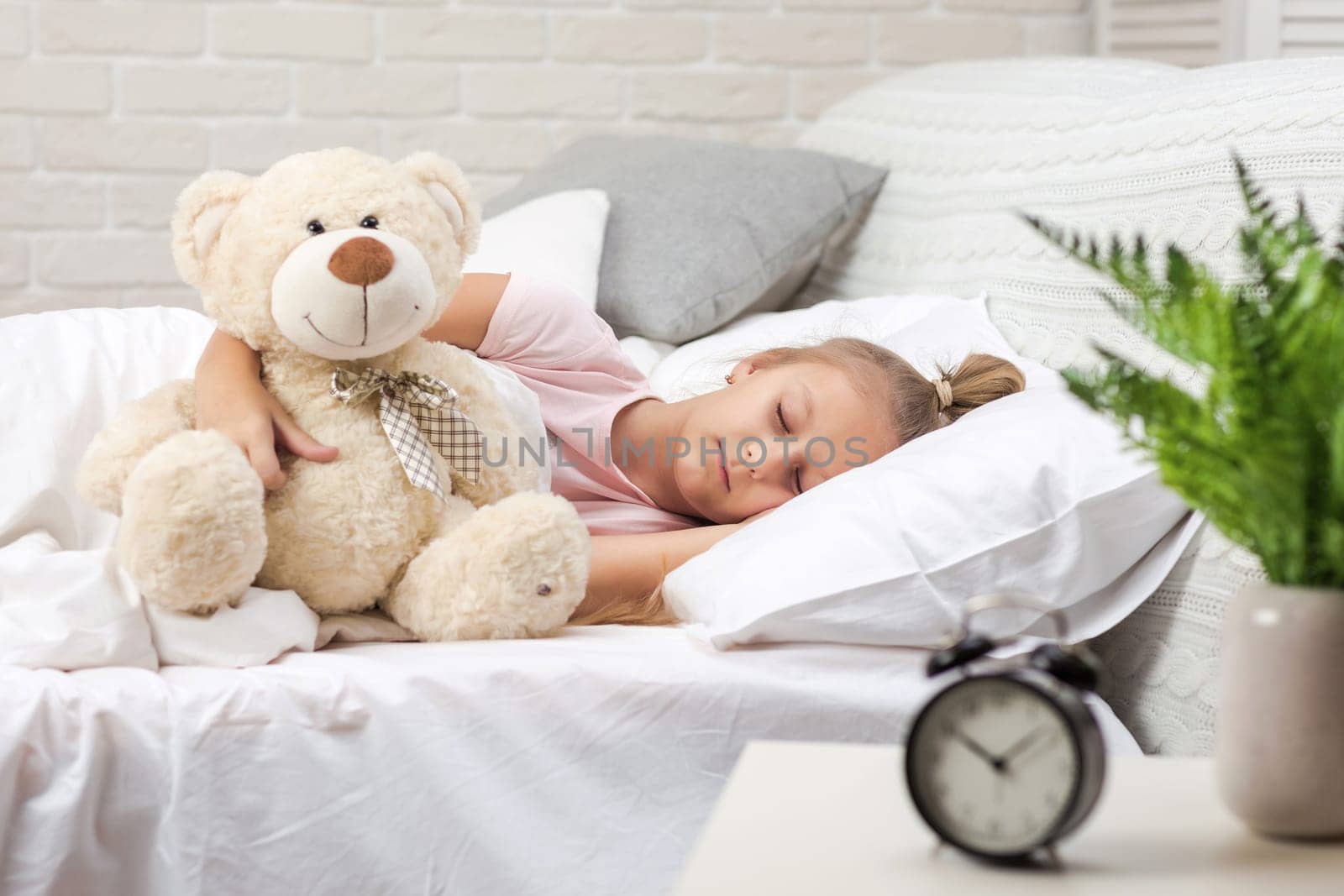 Cute little child girl sleeping with teddy bear in her bed