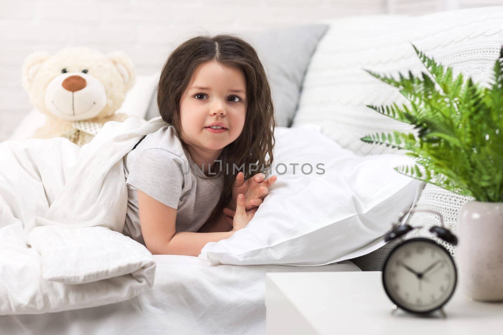cute little child girl wakes up from sleep in bed in the morning