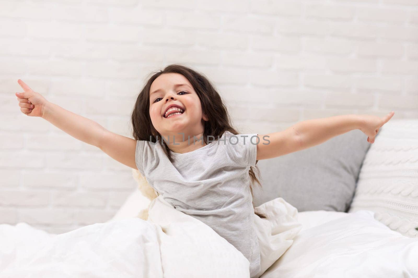 cute happy smiling little child girl wakes up from sleep in bed in the morning