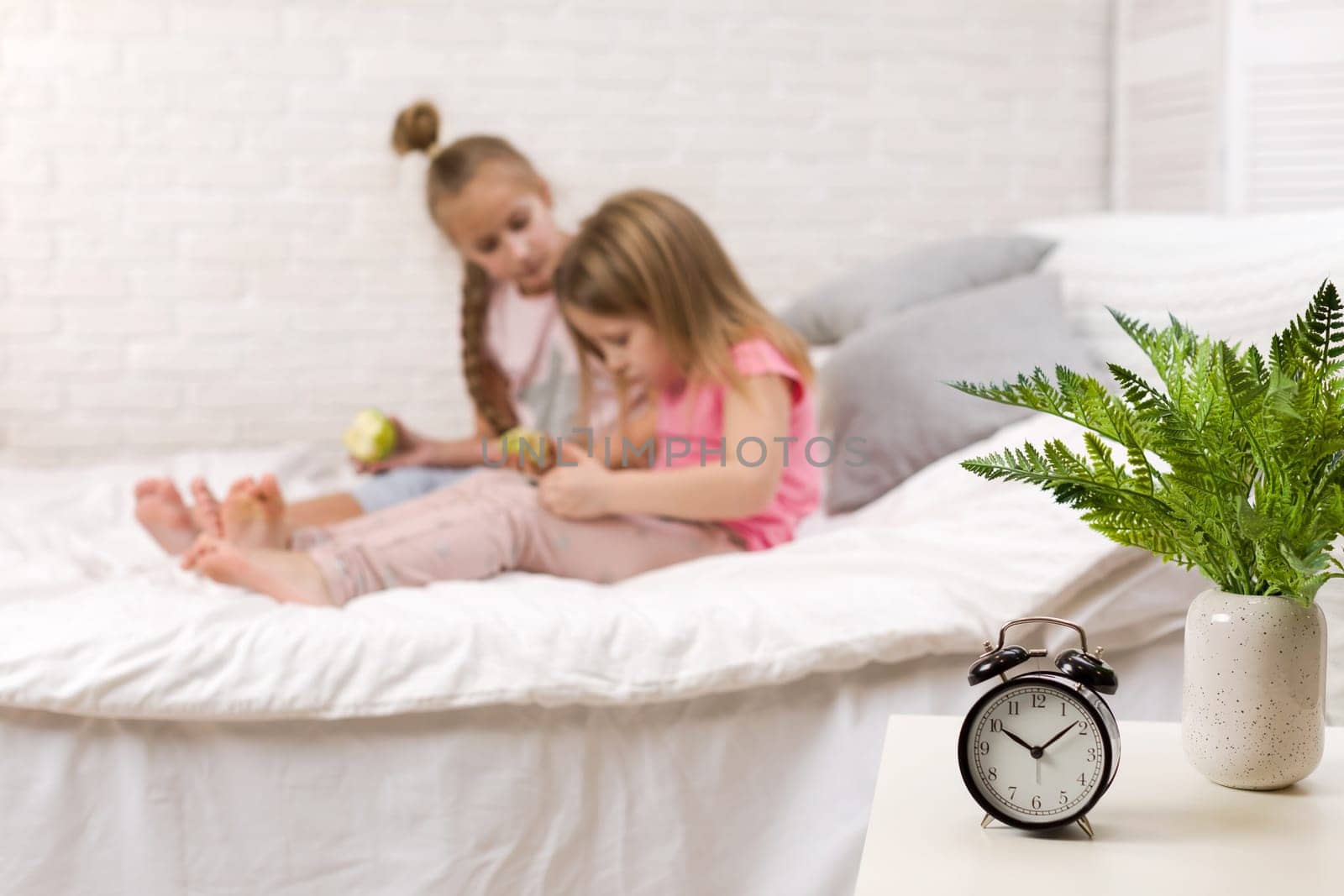 two cute children girls use digital tablet in bed. child playing on tablet pc.