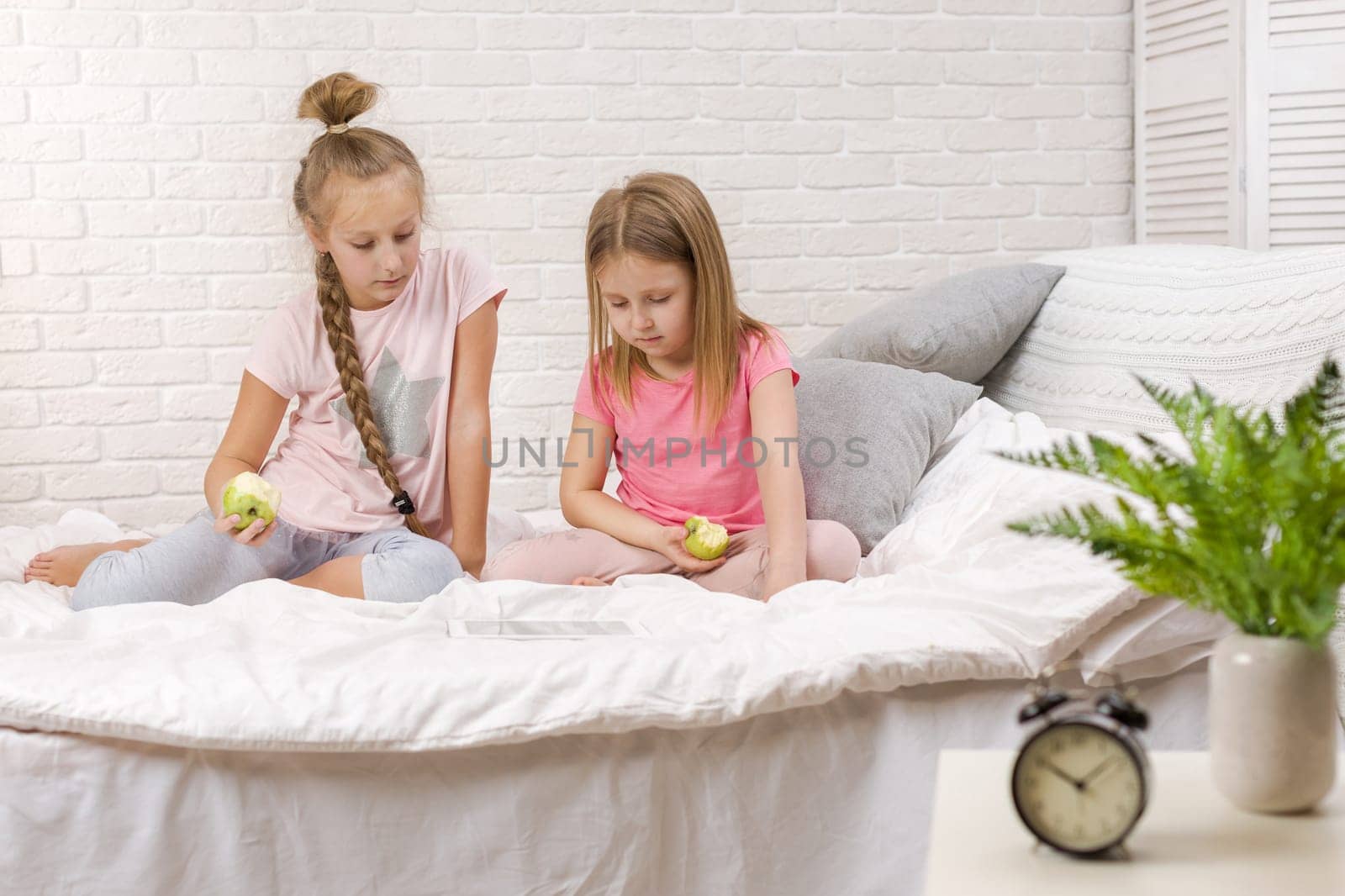 two cute children girls use digital tablet in bed. child playing on tablet pc.