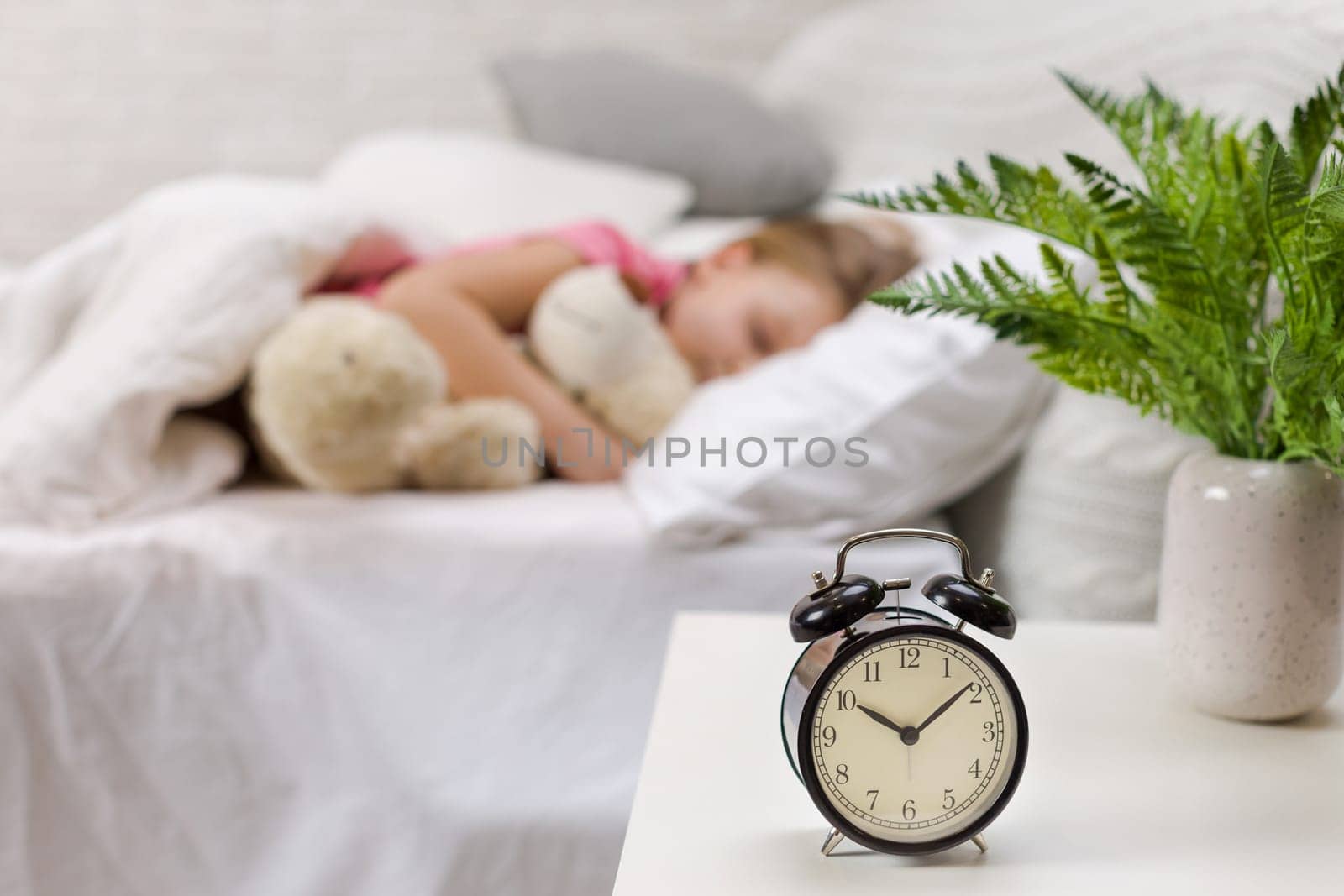 Cute little child girl sleeping with teddy bear in her bed