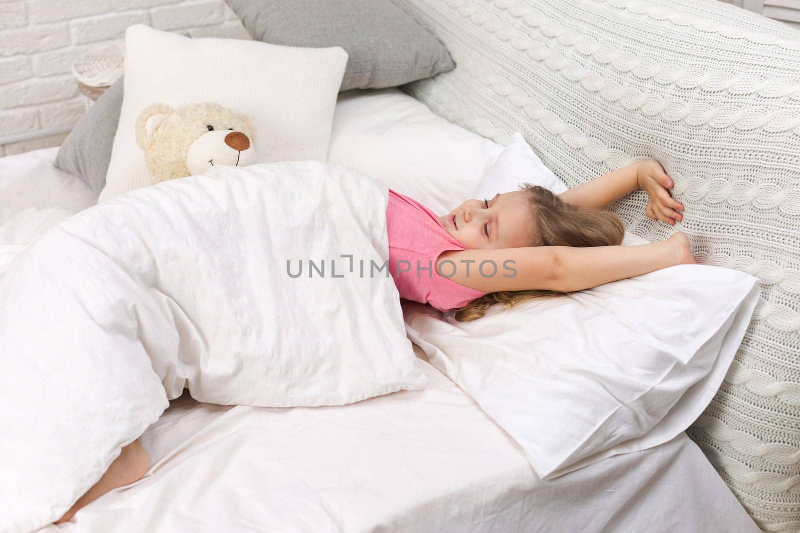 cute little child girl wakes up from sleep in bed in the morning