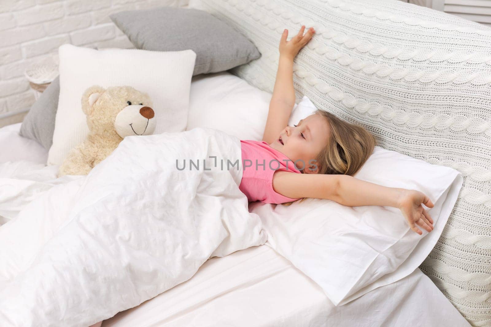 cute little child girl wakes up from sleep in bed in the morning