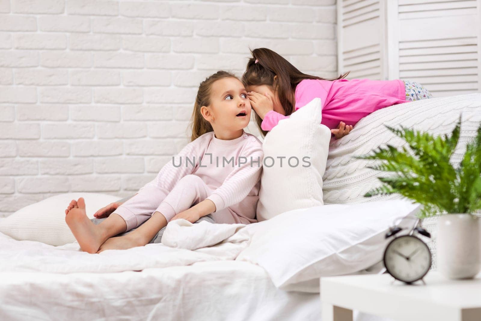 two cute children girls playing in the bedroom. pajama party and friendship.