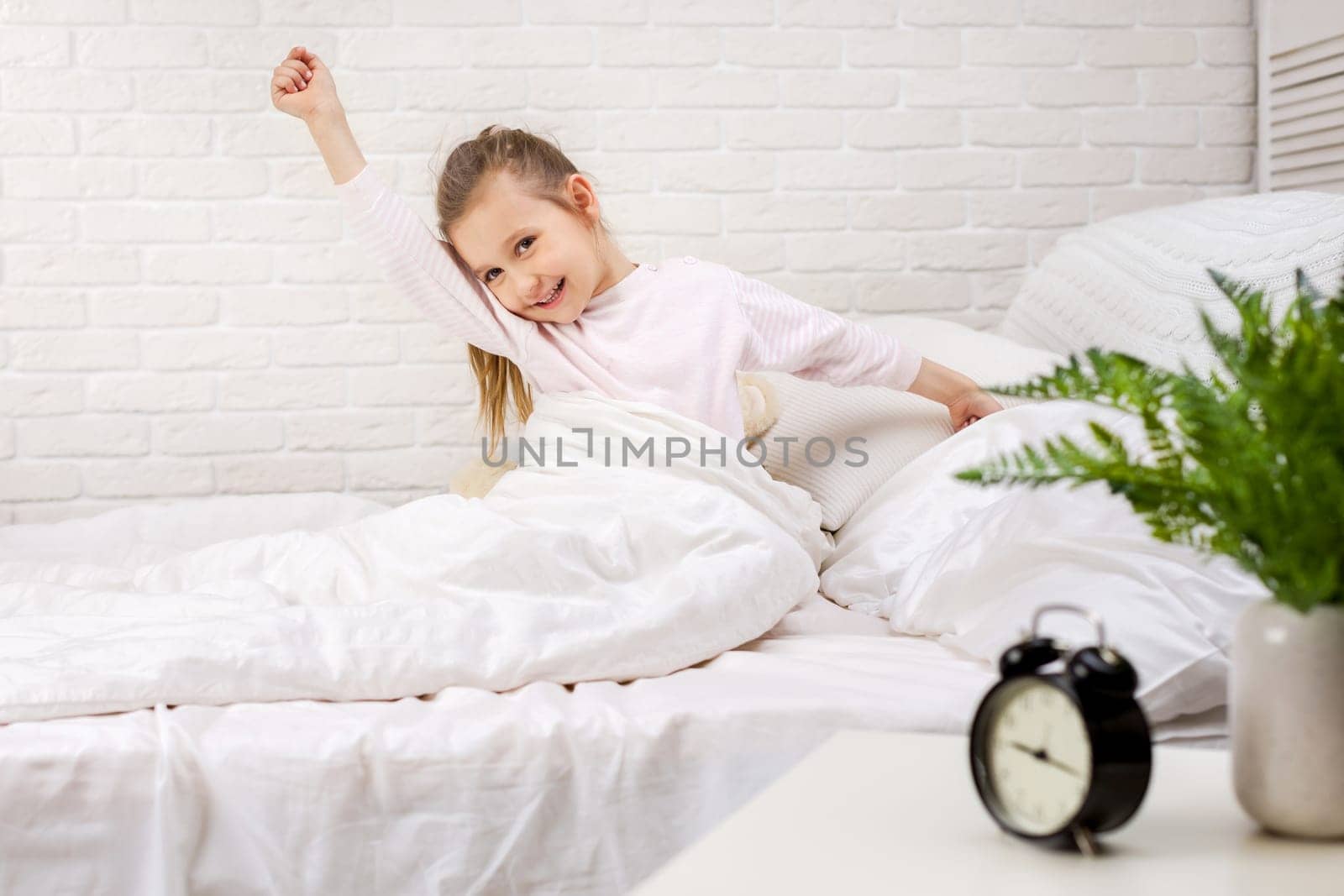 cute little child girl wakes up from sleep in bed in the morning