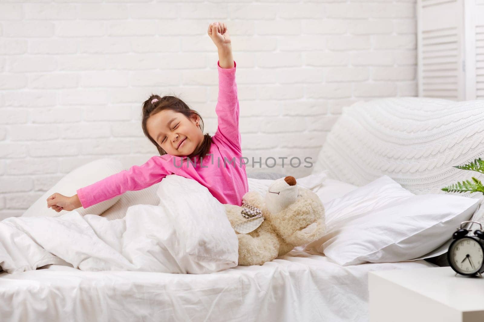cute little child girl wakes up from sleep and yawns in bed in the morning