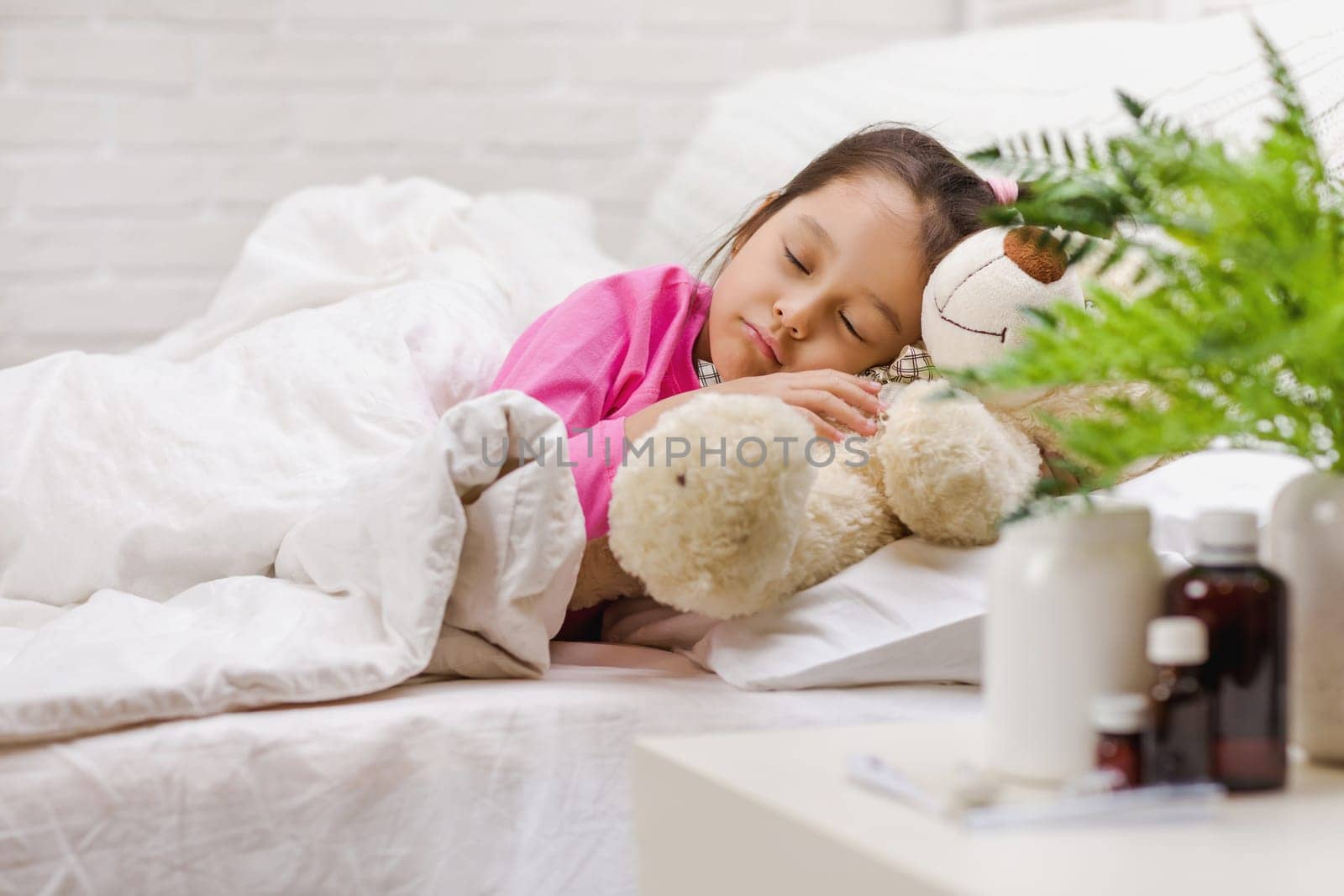Sick little child girl lying in bed with thermometer. Cold flu season