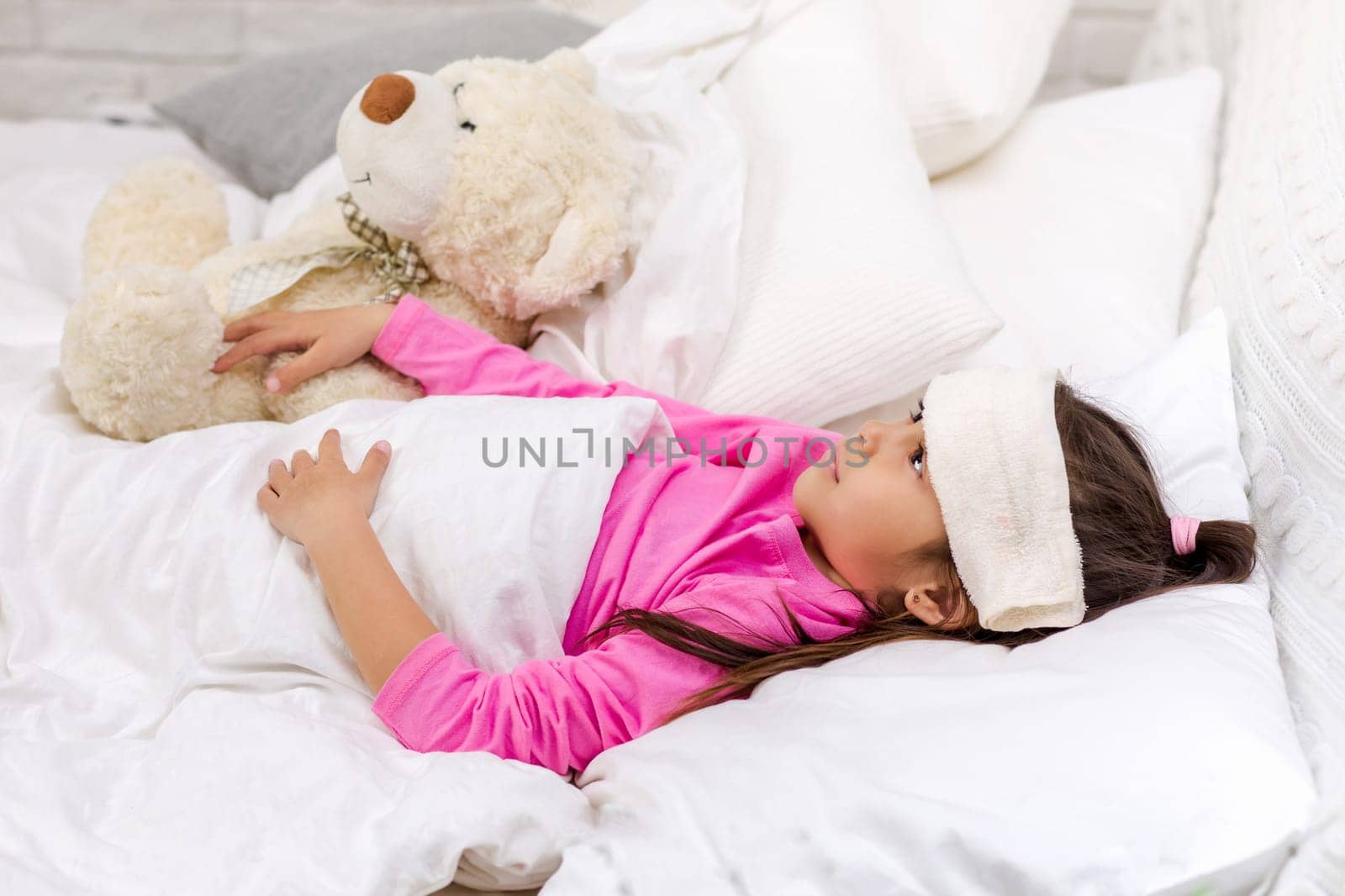 sick cold little child girl lies in bed with fever