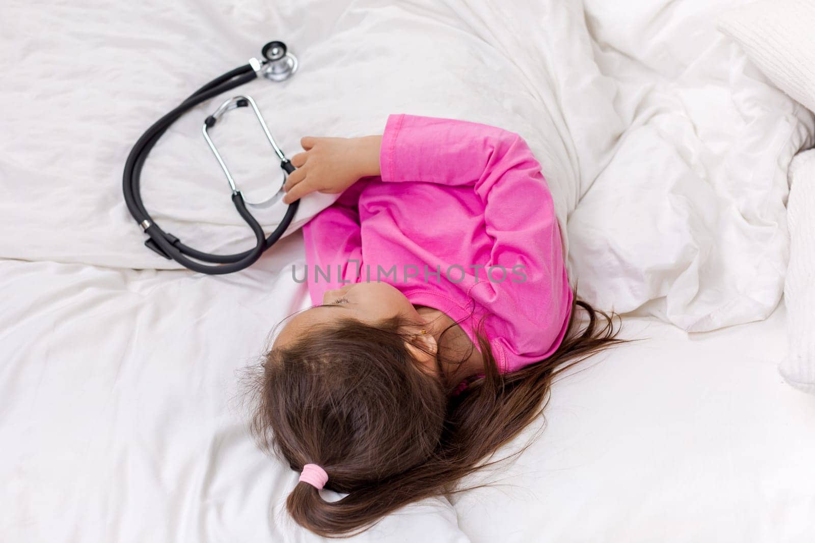 Sick little child girl lying in bed. top view