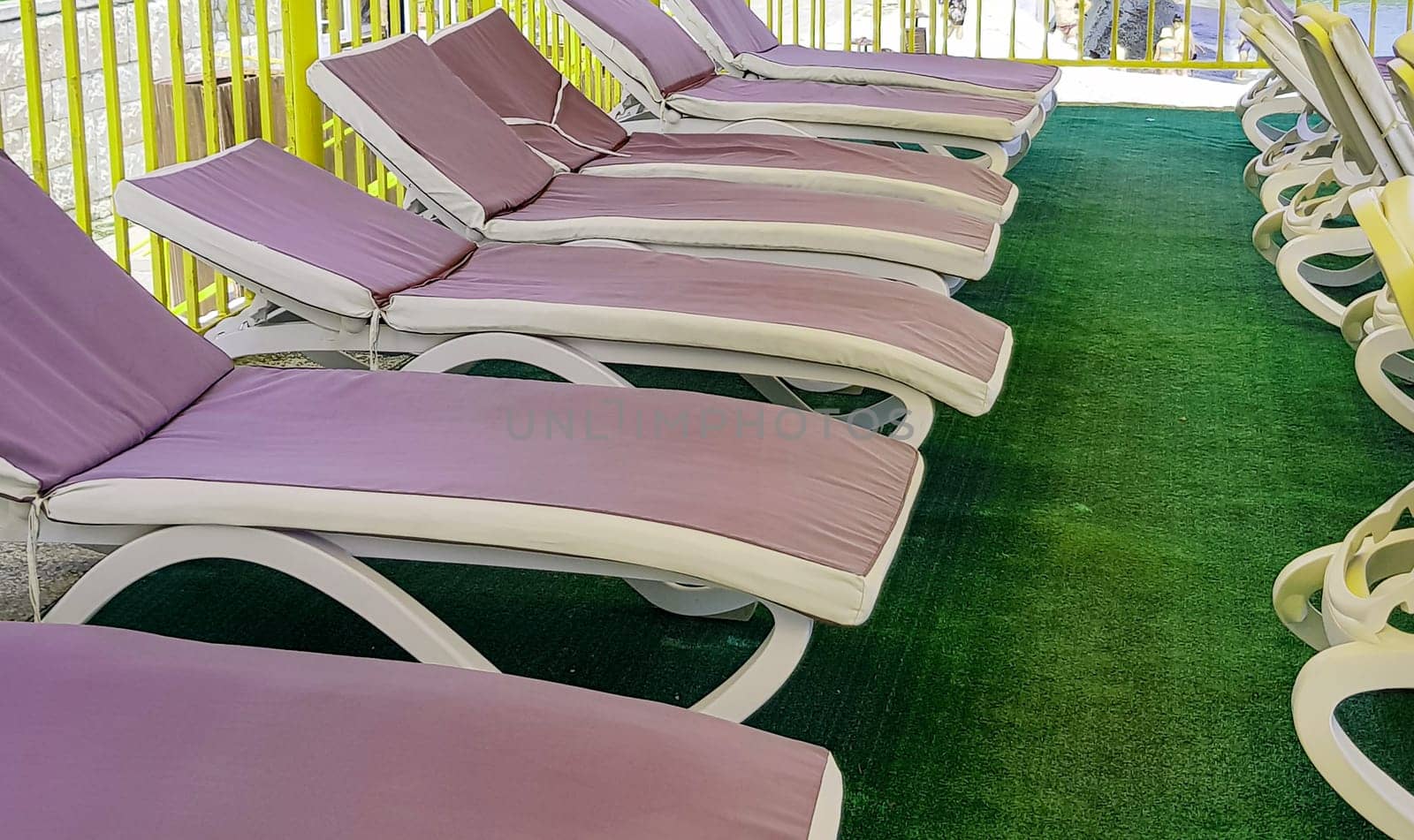 Free deck chairs stand in a row, empty beach chairs are waiting for tourists by claire_lucia