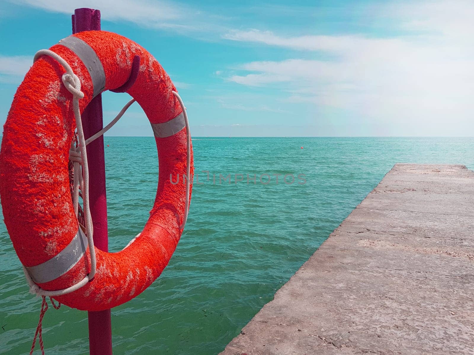 Lifebuoy on the background of the azure sea, sea pier in the sea, close-up, place for text.