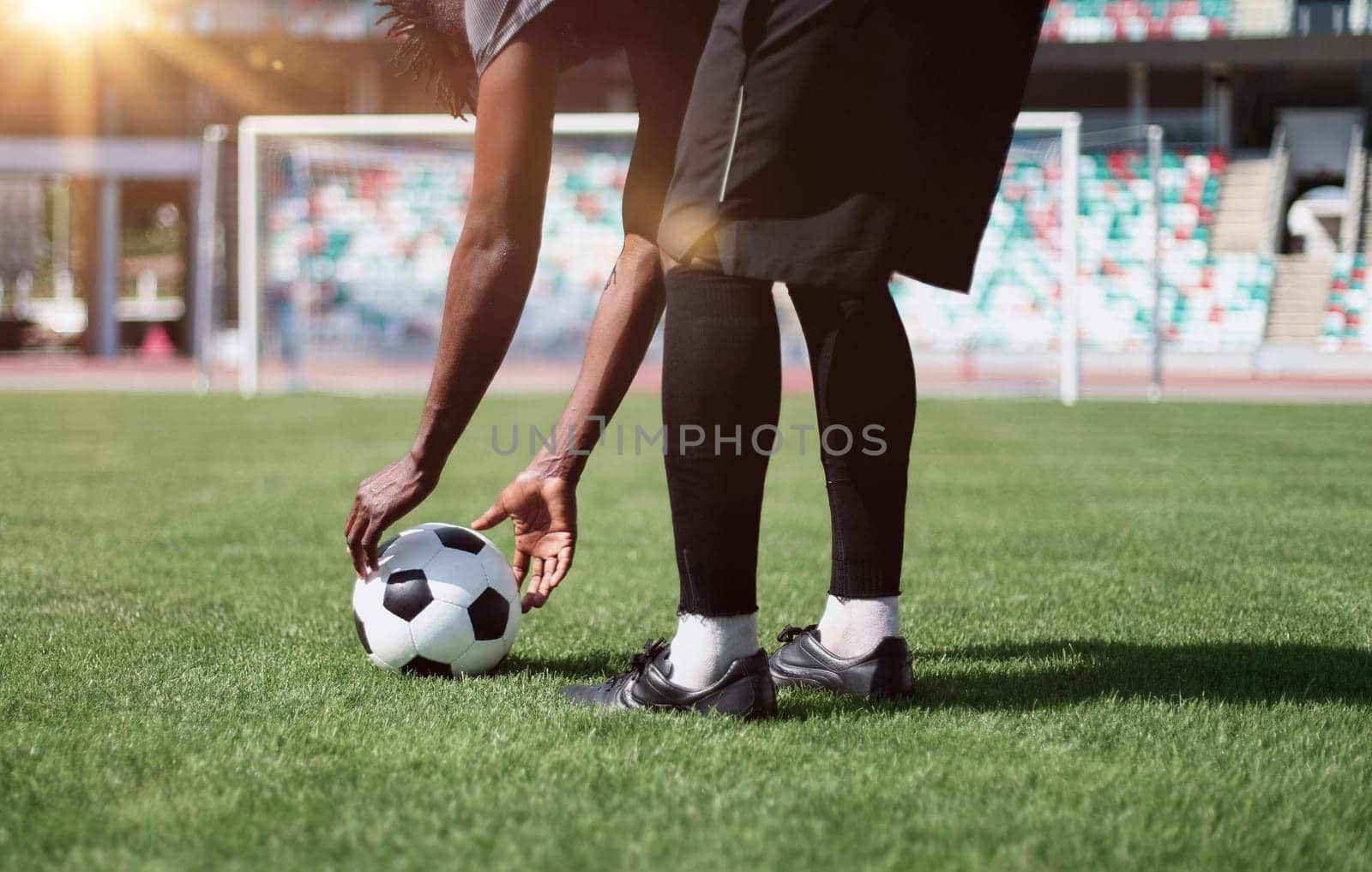 African American man playing football on the stadium field.