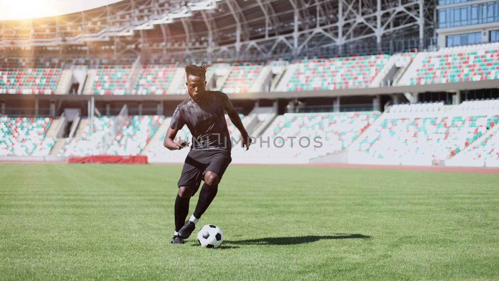 African American man playing football on the stadium field.