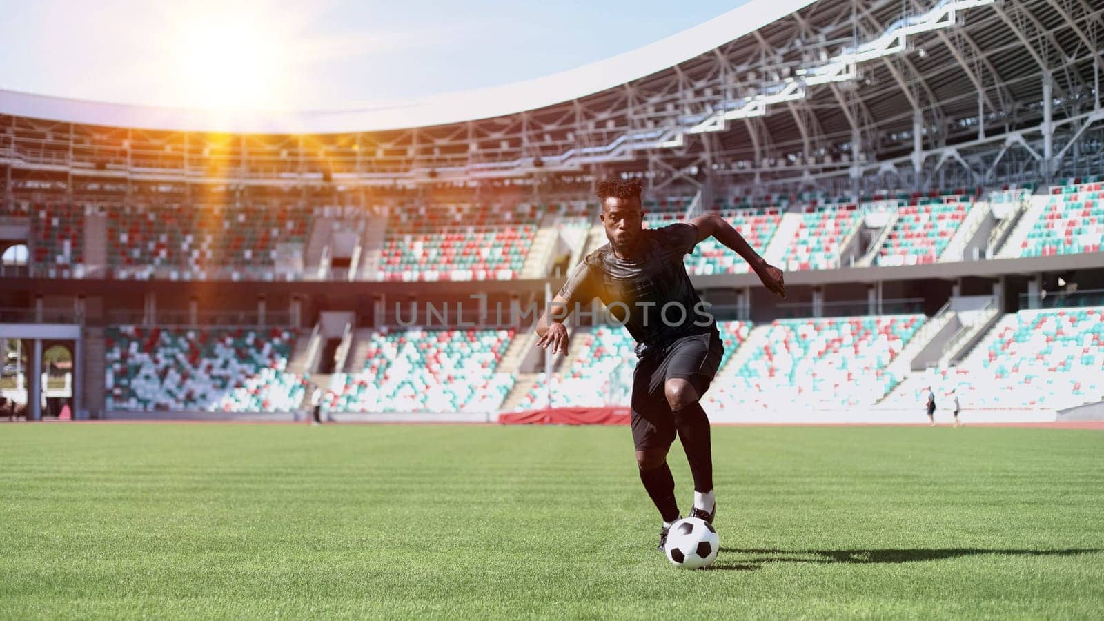 African American man playing football on the stadium field.