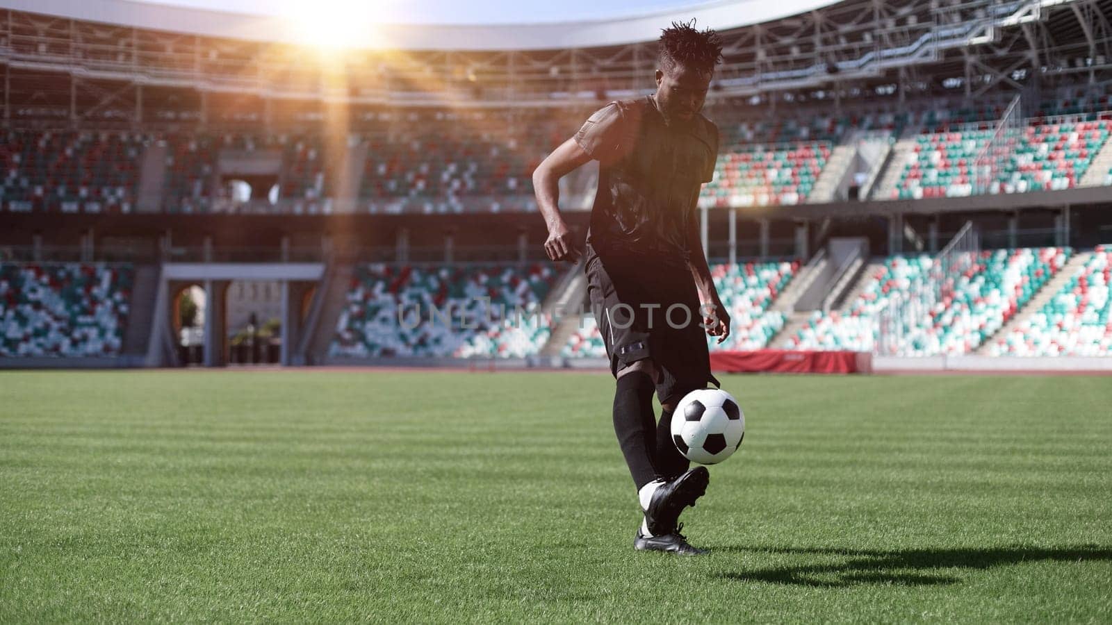 African American man playing football on the stadium field.
