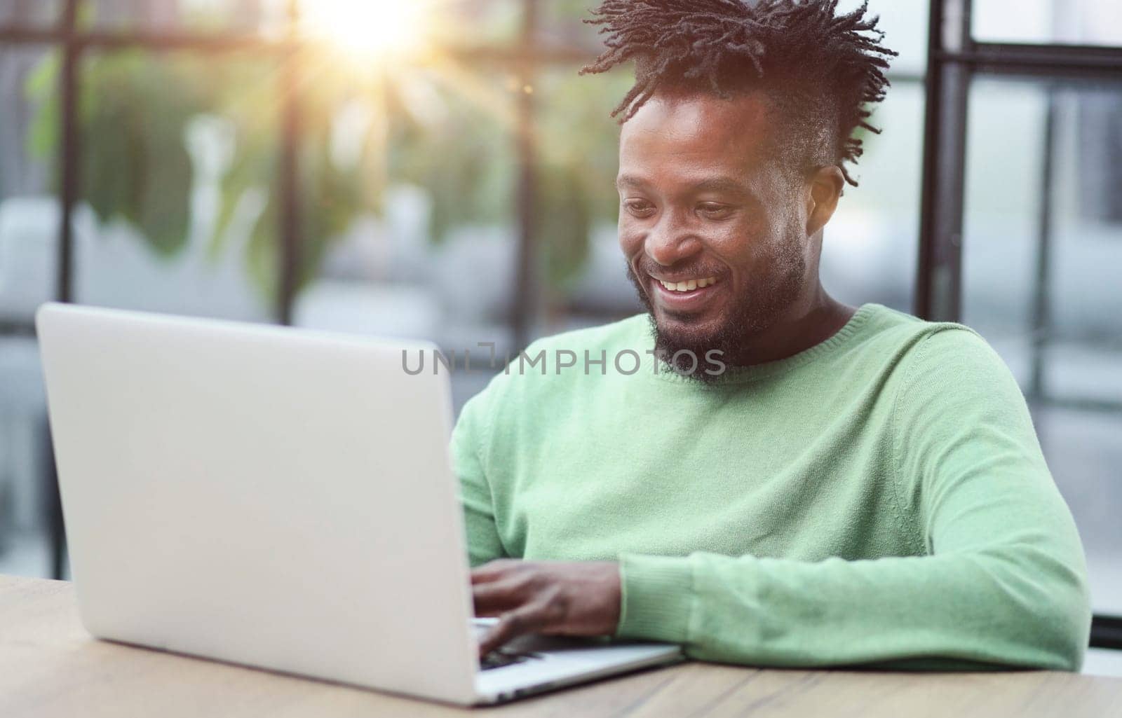 Young african american business man sitting in loft office or cafe, working on new online IT startup project, using laptop