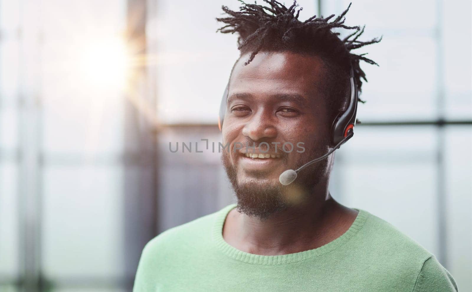 Operator of hot line. Portrait of cheerful african customer service representative with headset in call center, empty space