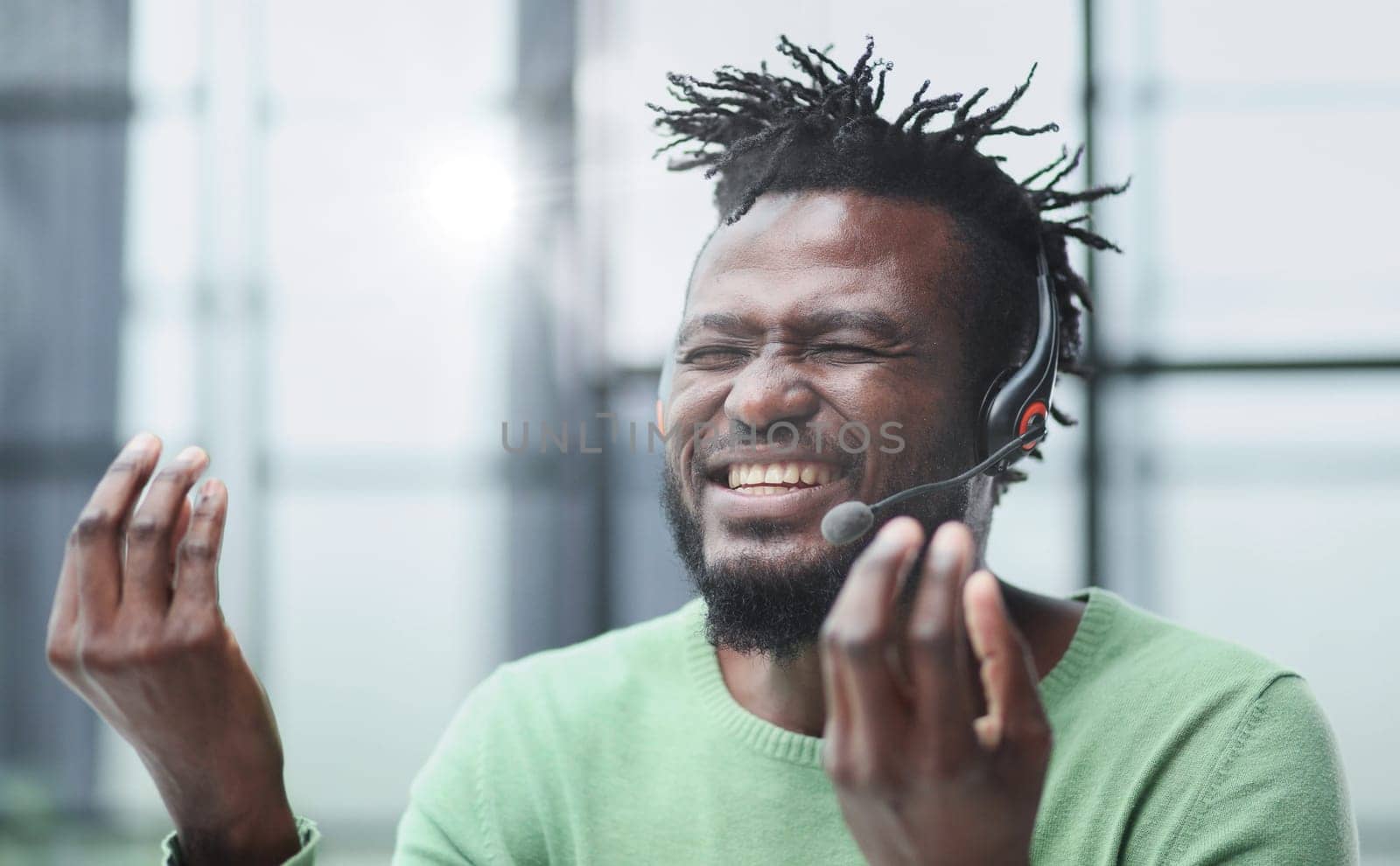 Operator of hot line. Portrait of cheerful african customer service representative with headset in call center, empty space