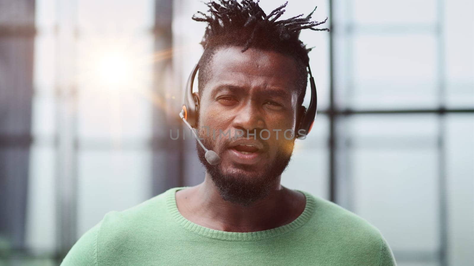 Operator of hot line. Portrait of cheerful african customer service representative with headset in call center, empty space