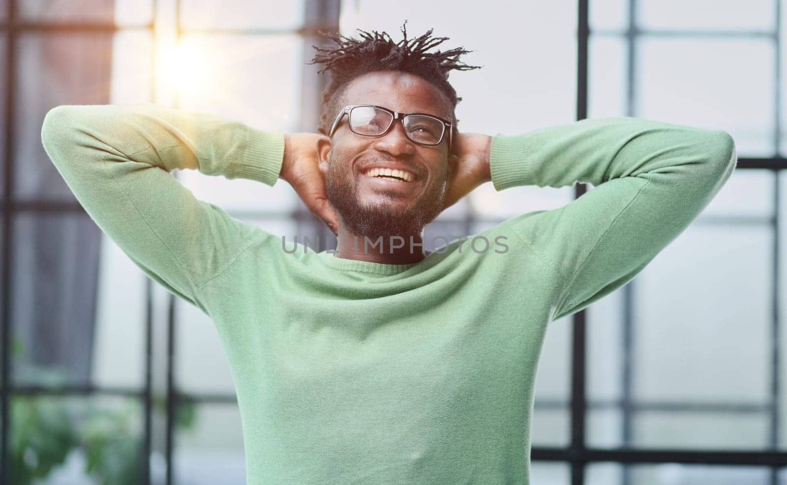 a young man in a green sweatshirt clasped his hands behind his head.