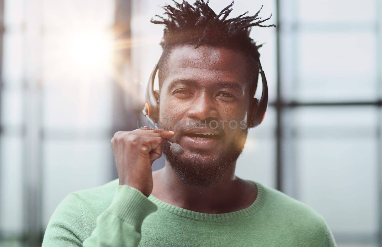 Operator of hot line. Portrait of cheerful african customer service representative with headset in call center, empty space