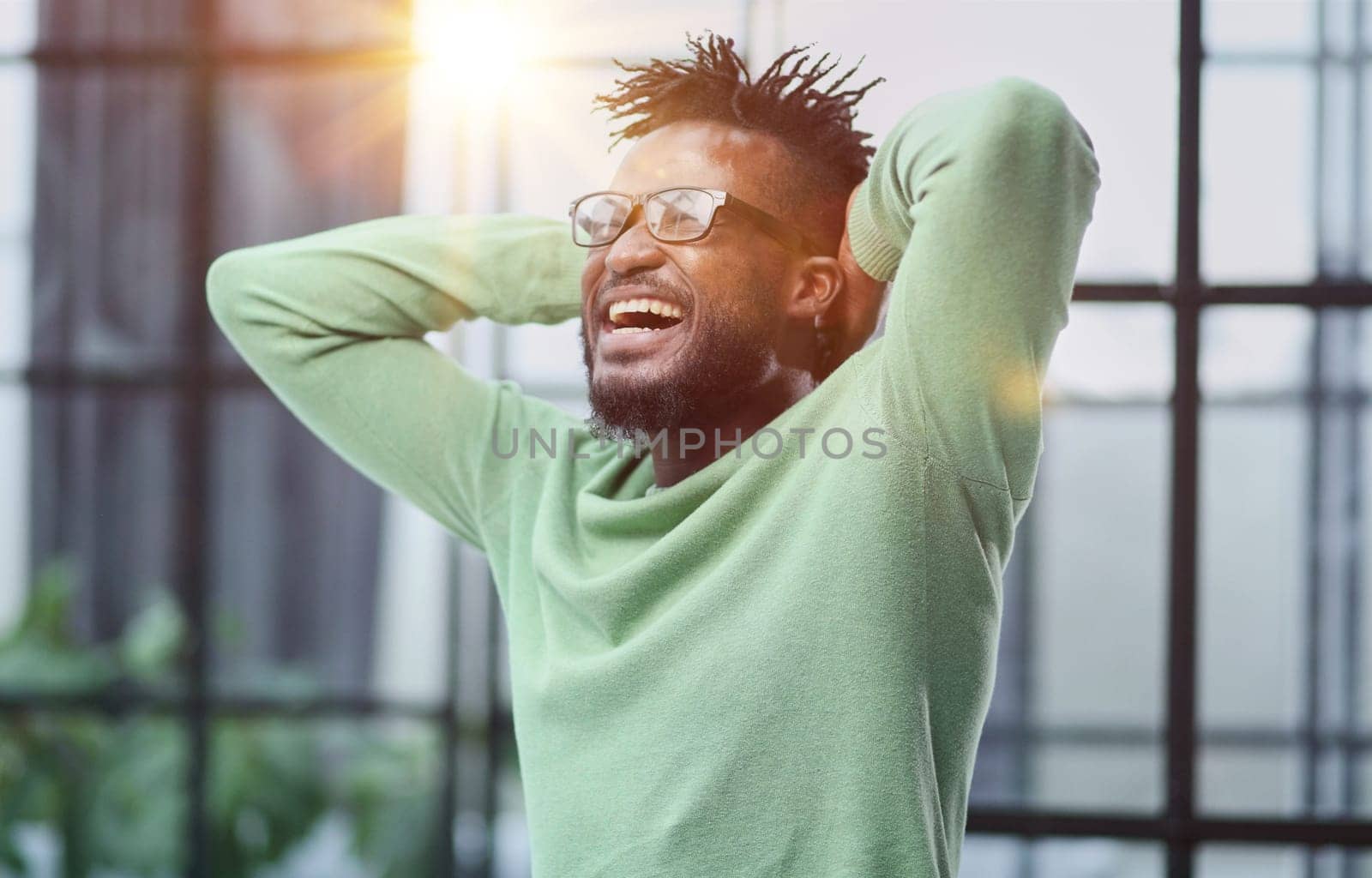 a young man in a green sweatshirt clasped his hands behind his head.
