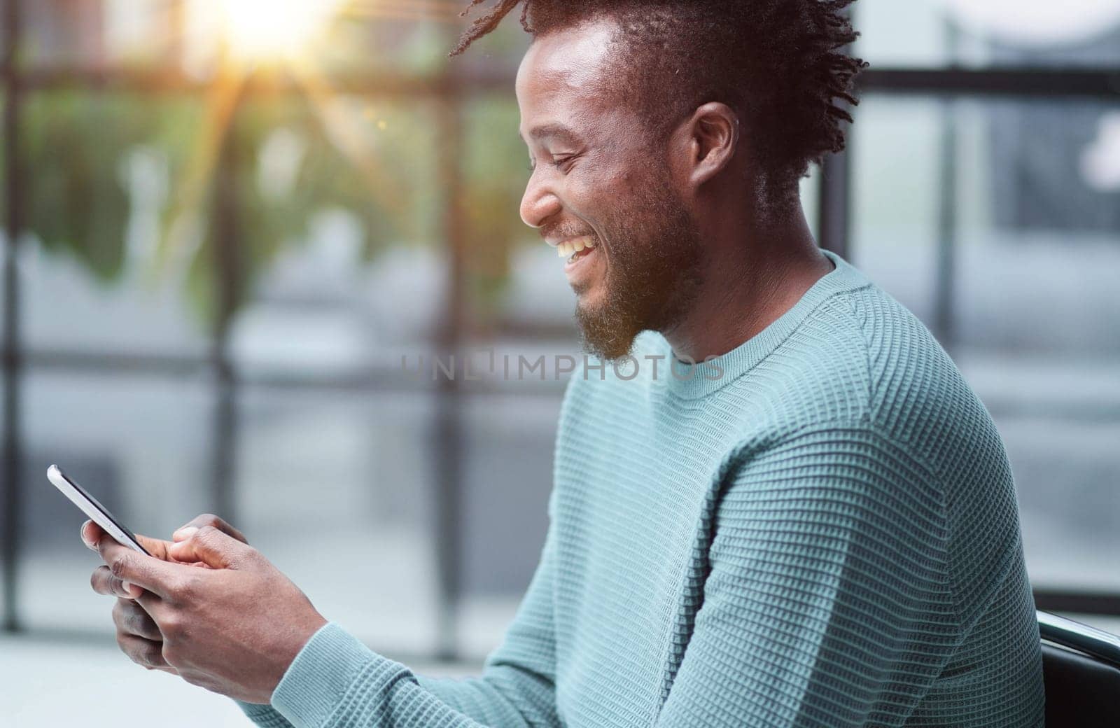 Black man looking at smartphone browsing internet, office technology and digital communication