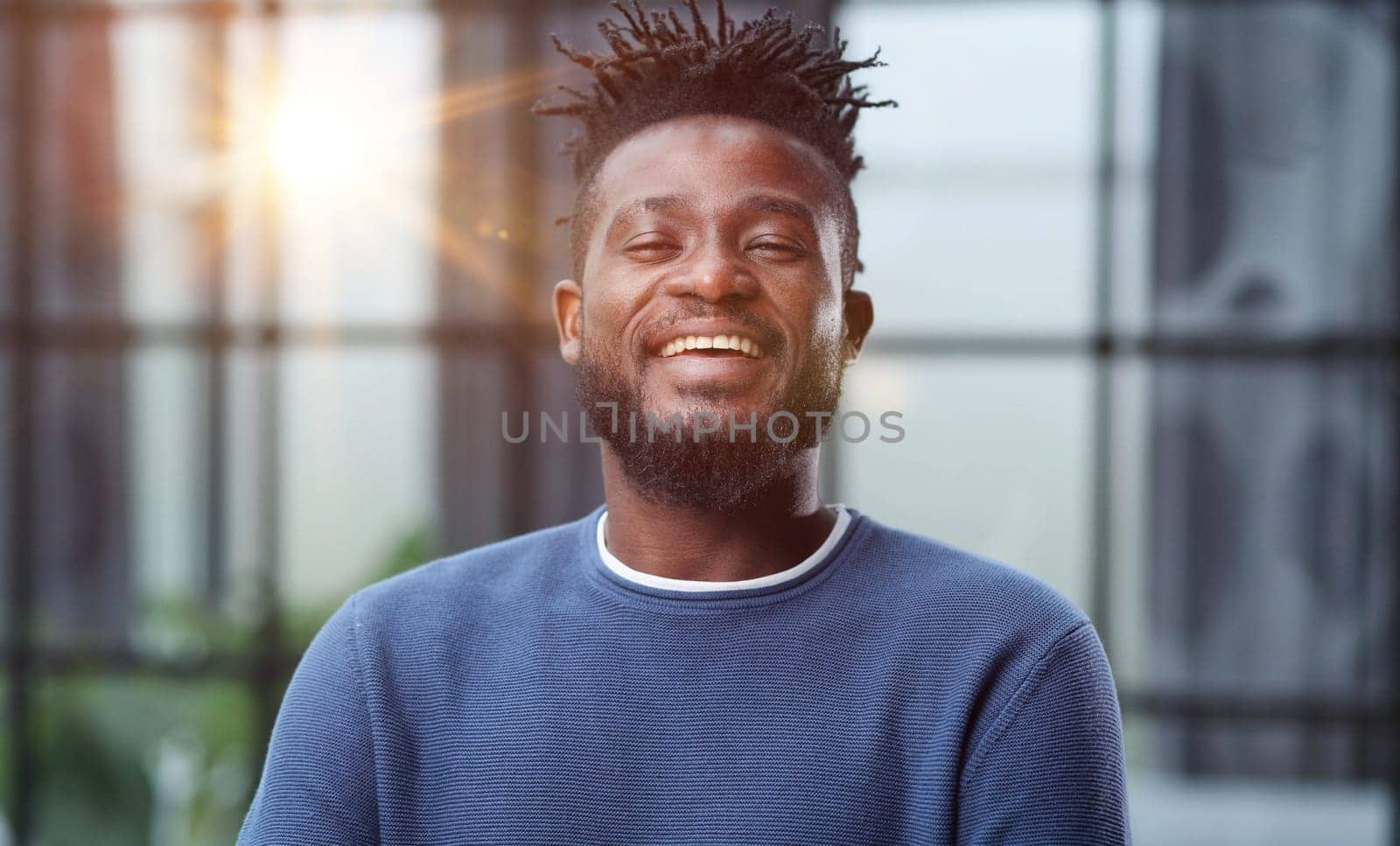 Handsome charming cheerful african american businessman in chic colorful casual clothes, in an office building