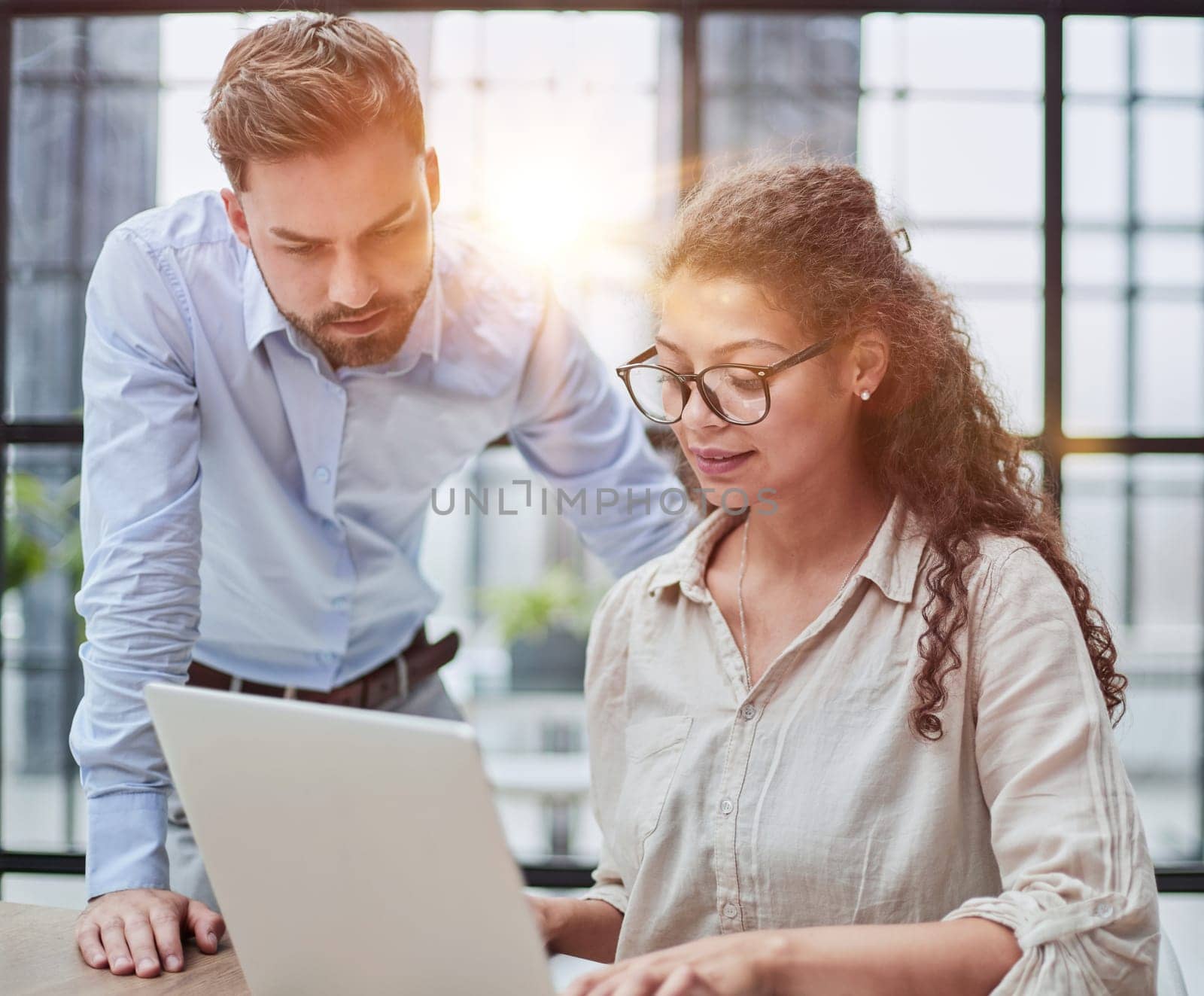Colleagues check documents using a laptop. A man and a woman are sitting together looking at a laptop. business concept