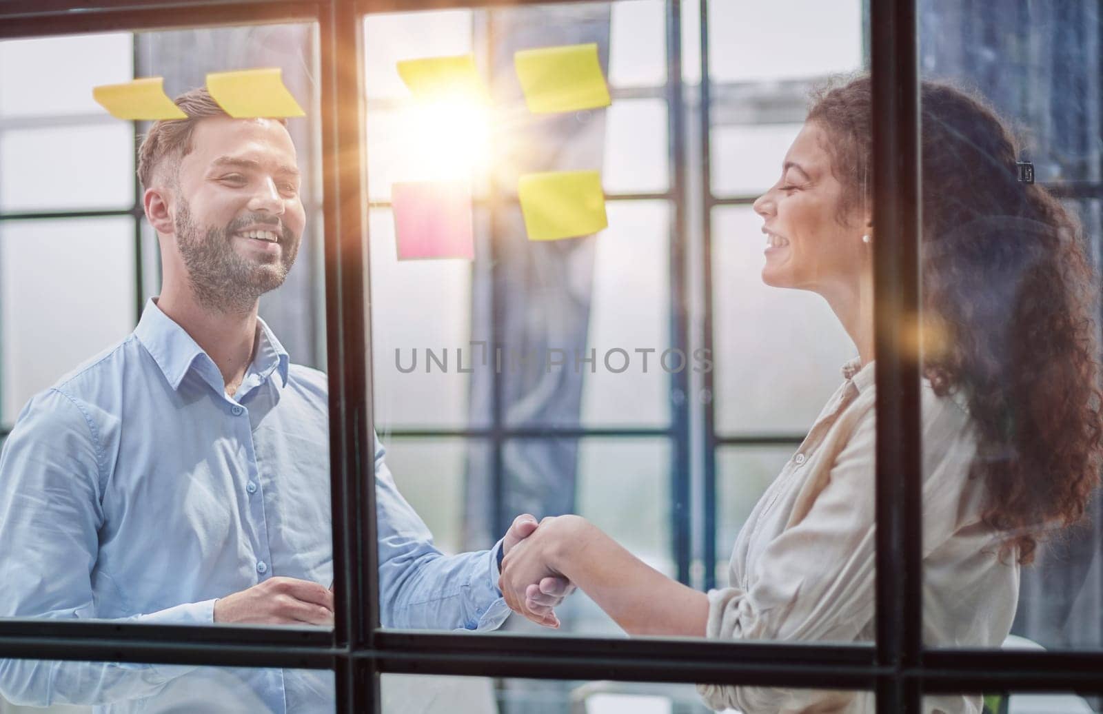 Business people talking in the hallway of the modern office building with employees working behind glass partitions. Work in a large business corporation