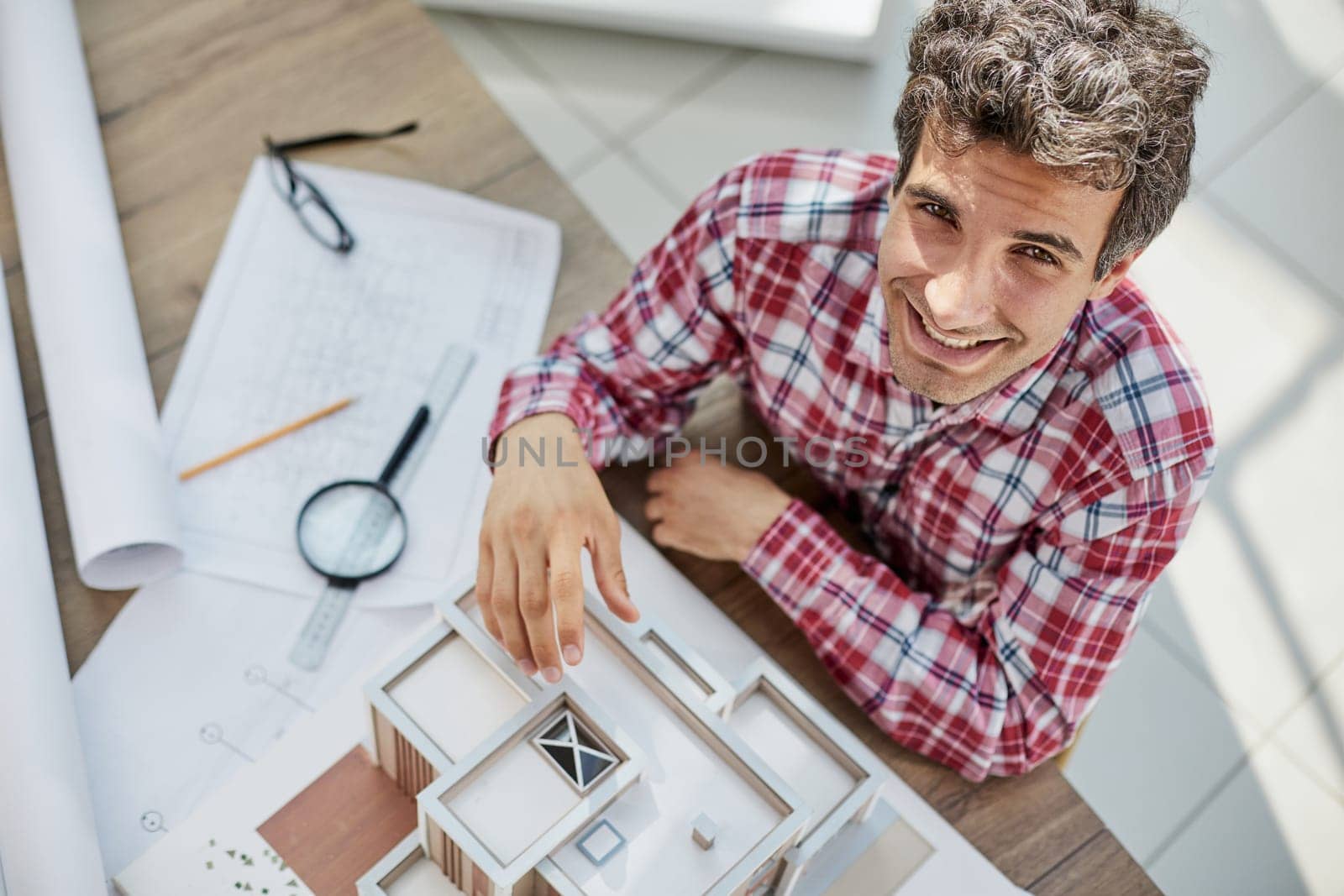 Male architect holding and working on model of architectural house top view