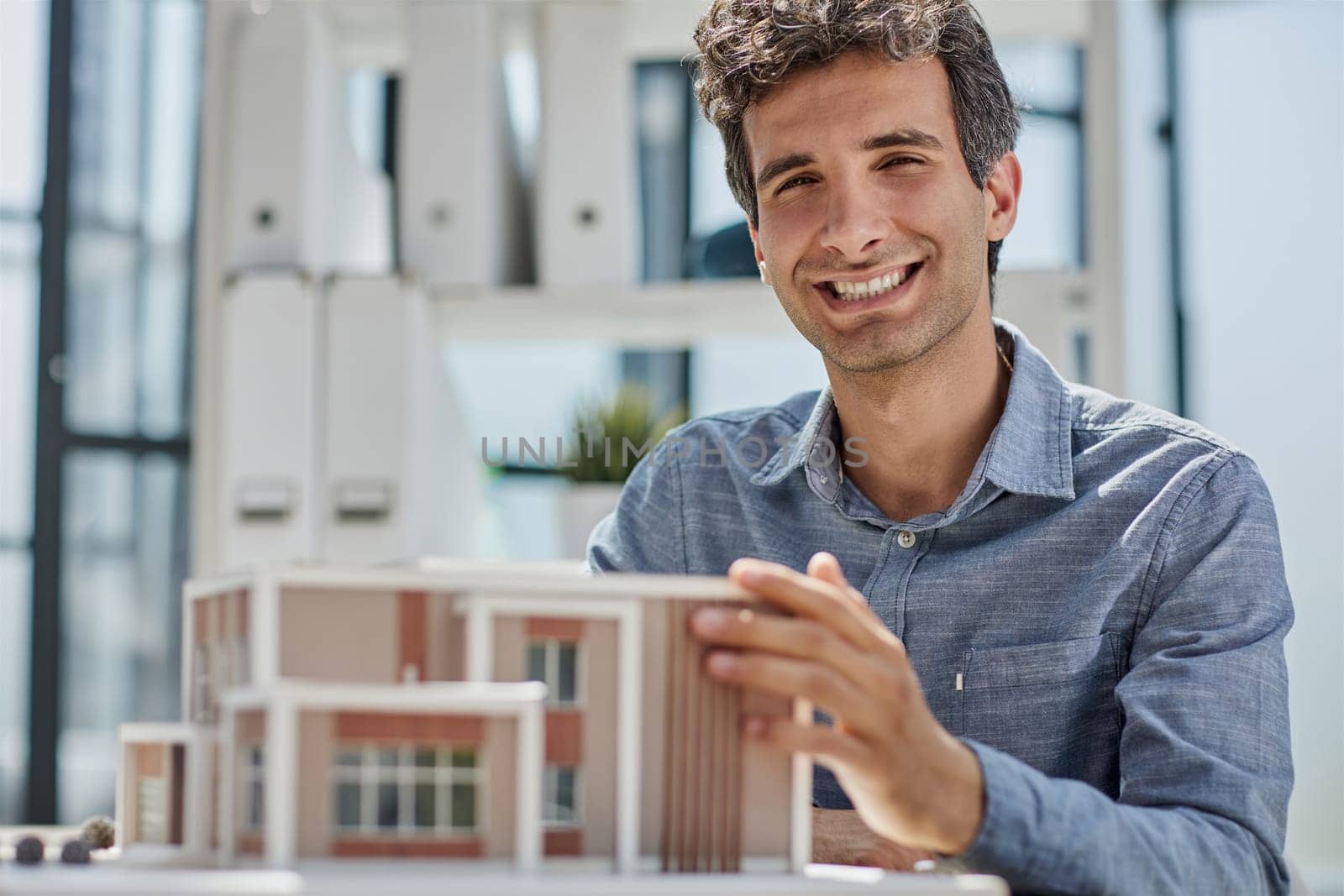 young caucasian engineer man making building model with the use of drawings and notes in office. smart designer assembles a complex structure
