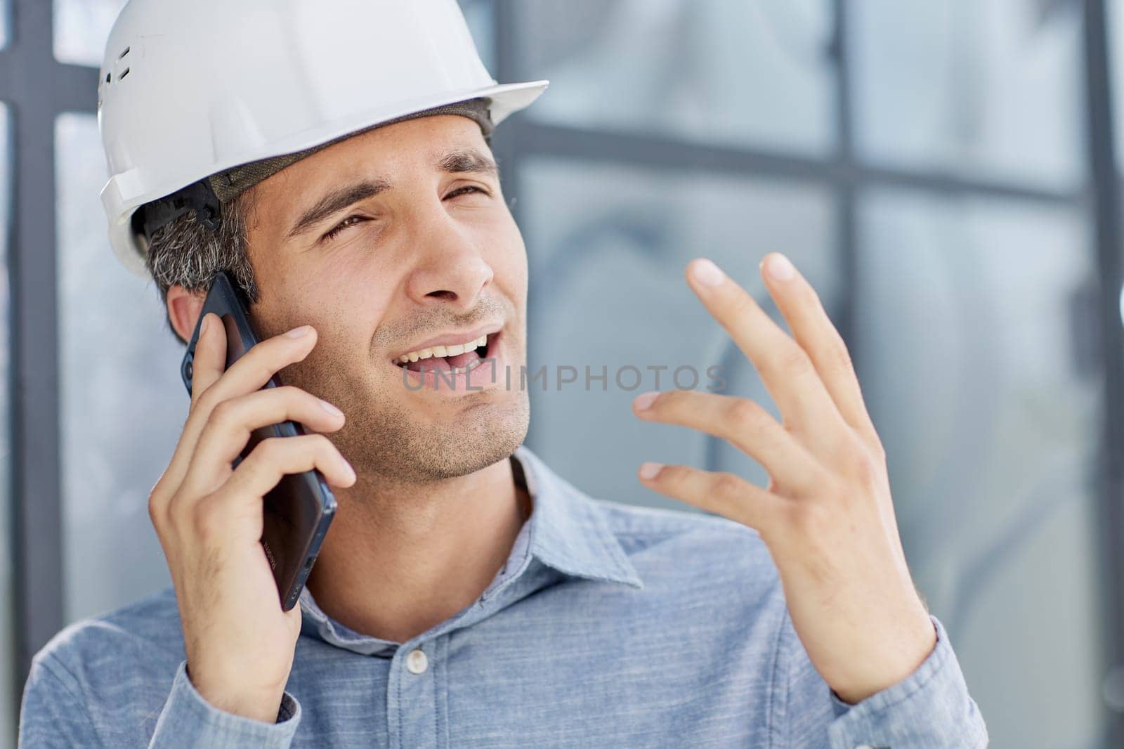 smiling architect in a hard hat speaks on a smartphone.