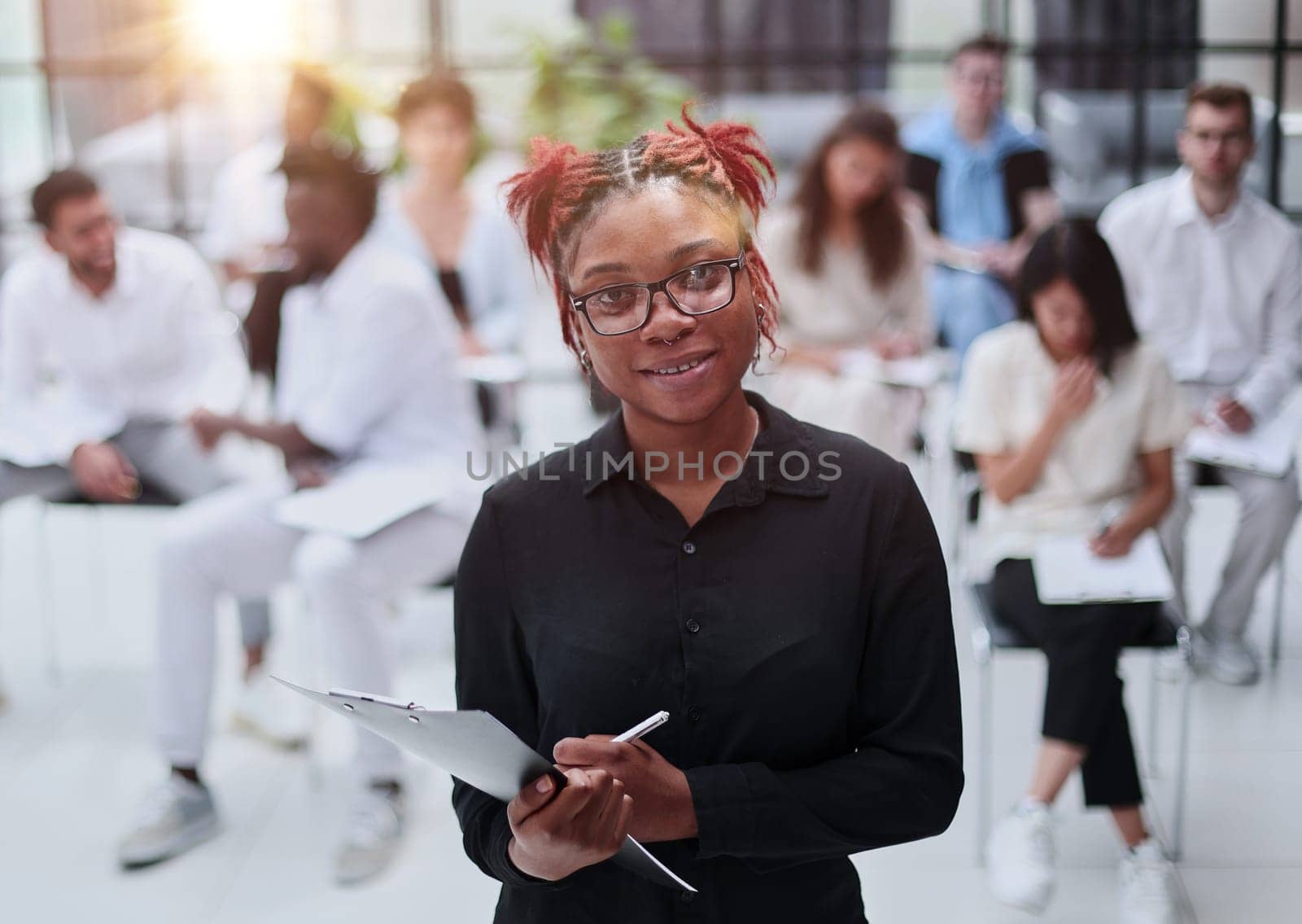 african american woman with a notepad against the background of other people at the seminar. business concept