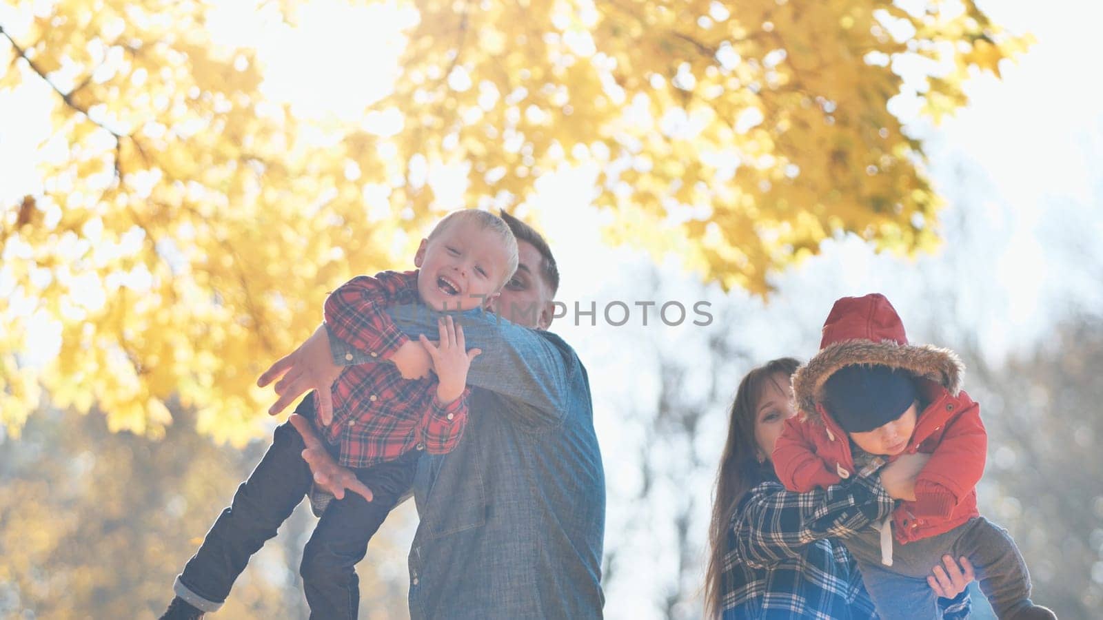 A young, fun family playing with their children in the park in the fall